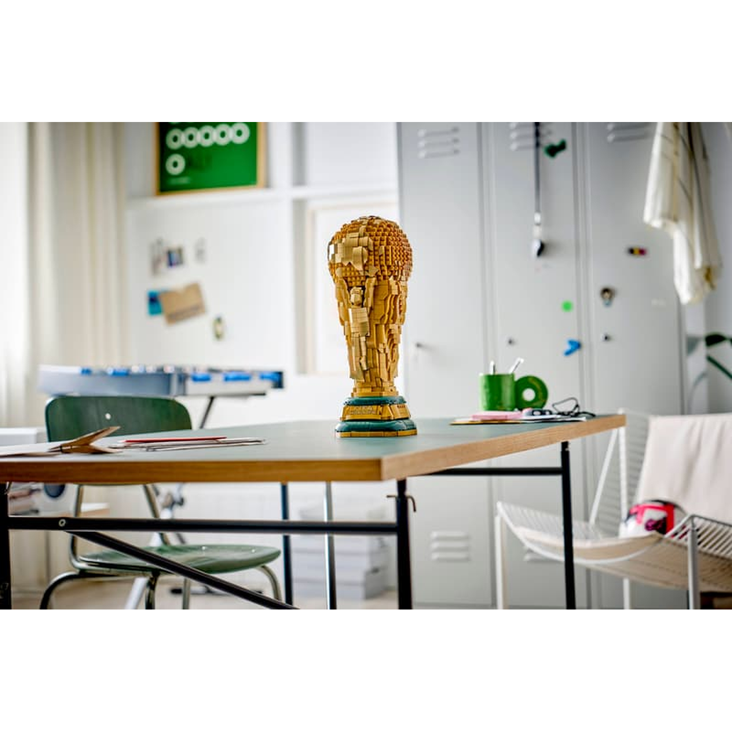 Un trophée en blocs de bois sur une table. Casier et ballon de foot en arrière-plan.