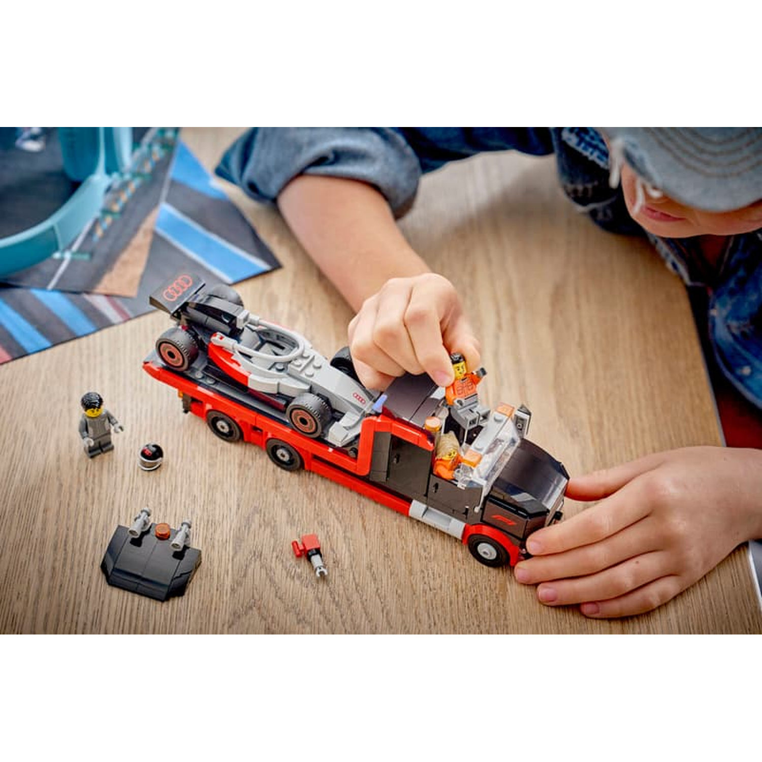 Een kind speelt met een Lego raceautotransporter en een Formule 1 auto.
