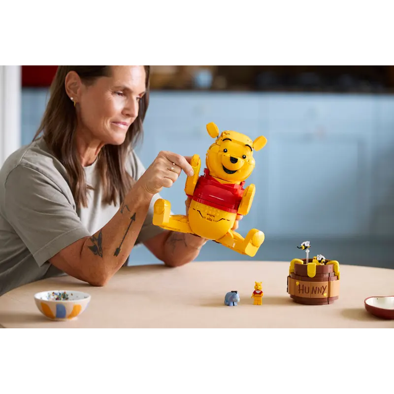 Een vrouw bouwt Winnie de Poeh van Lego, met een honingpot ernaast.