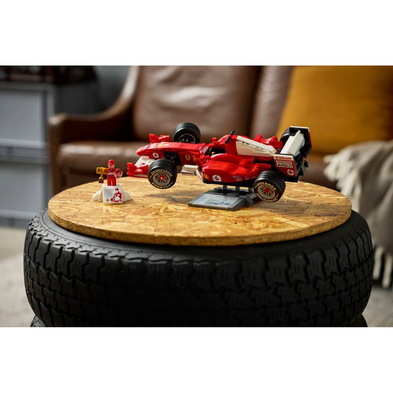 Une voiture de course Lego Formule 1 rouge et une figurine sur une table en bois sur base de pneu.