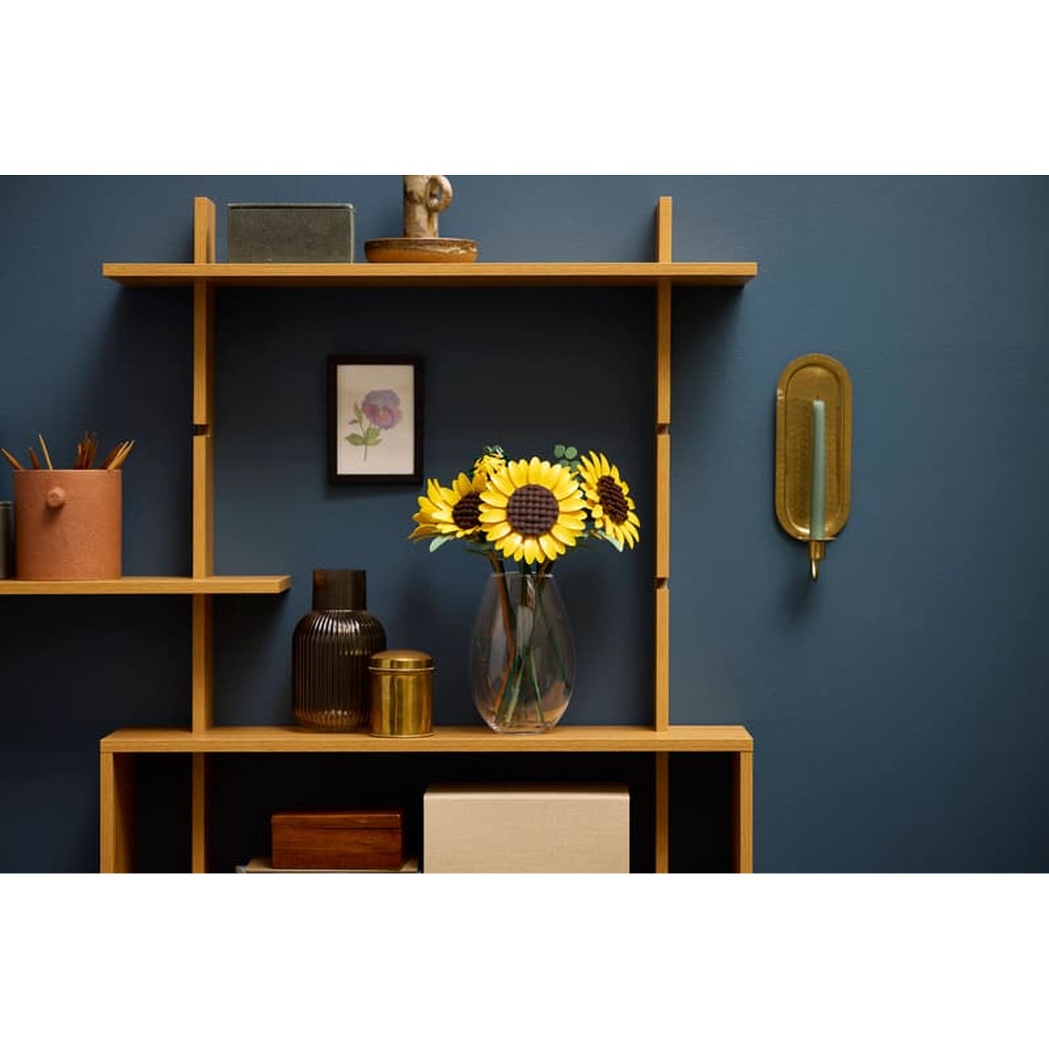 Une étagère avec des tournesols, des vases et des objets décoratifs sur un mur bleu.