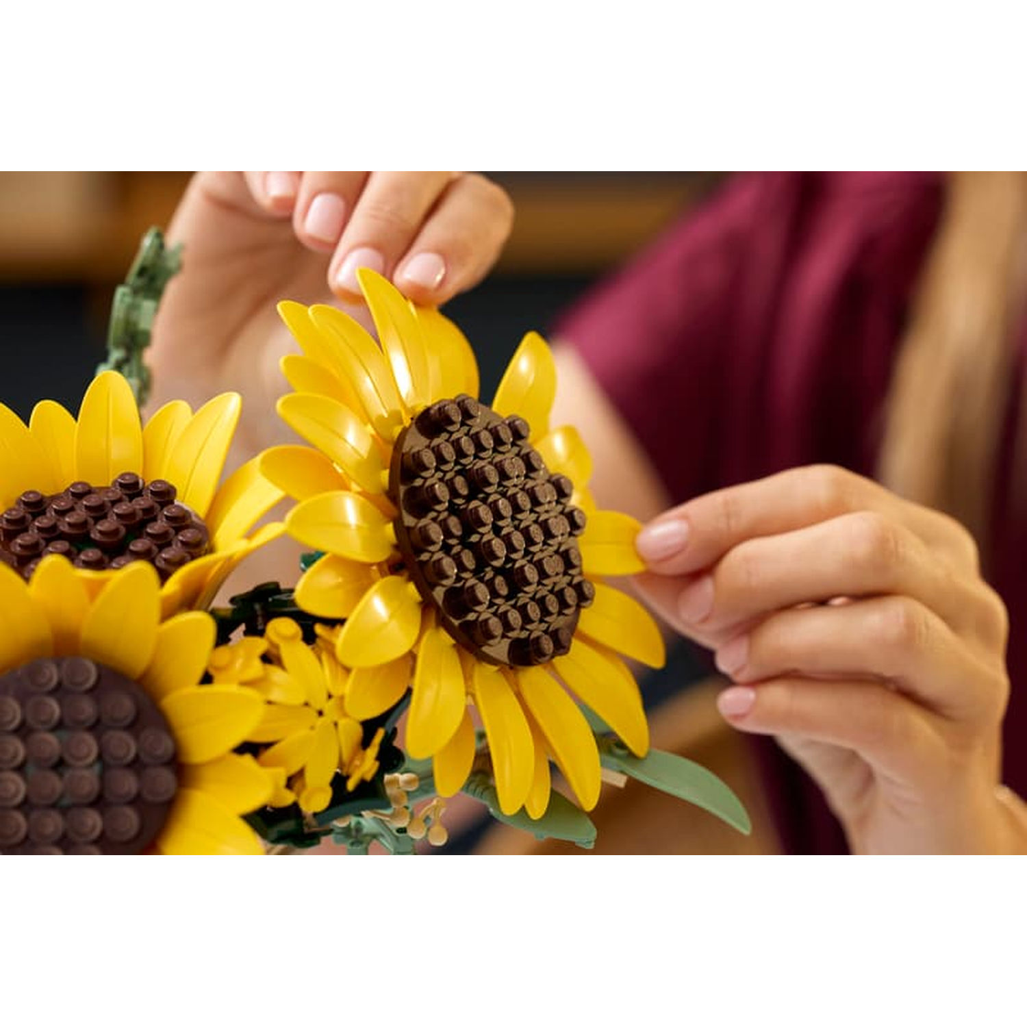Mains assemblant des tournesols Lego jaunes aux centres bruns.