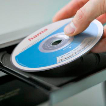 Eine Hand führt eine CD in ein Laufwerk ein, Nahaufnahme.