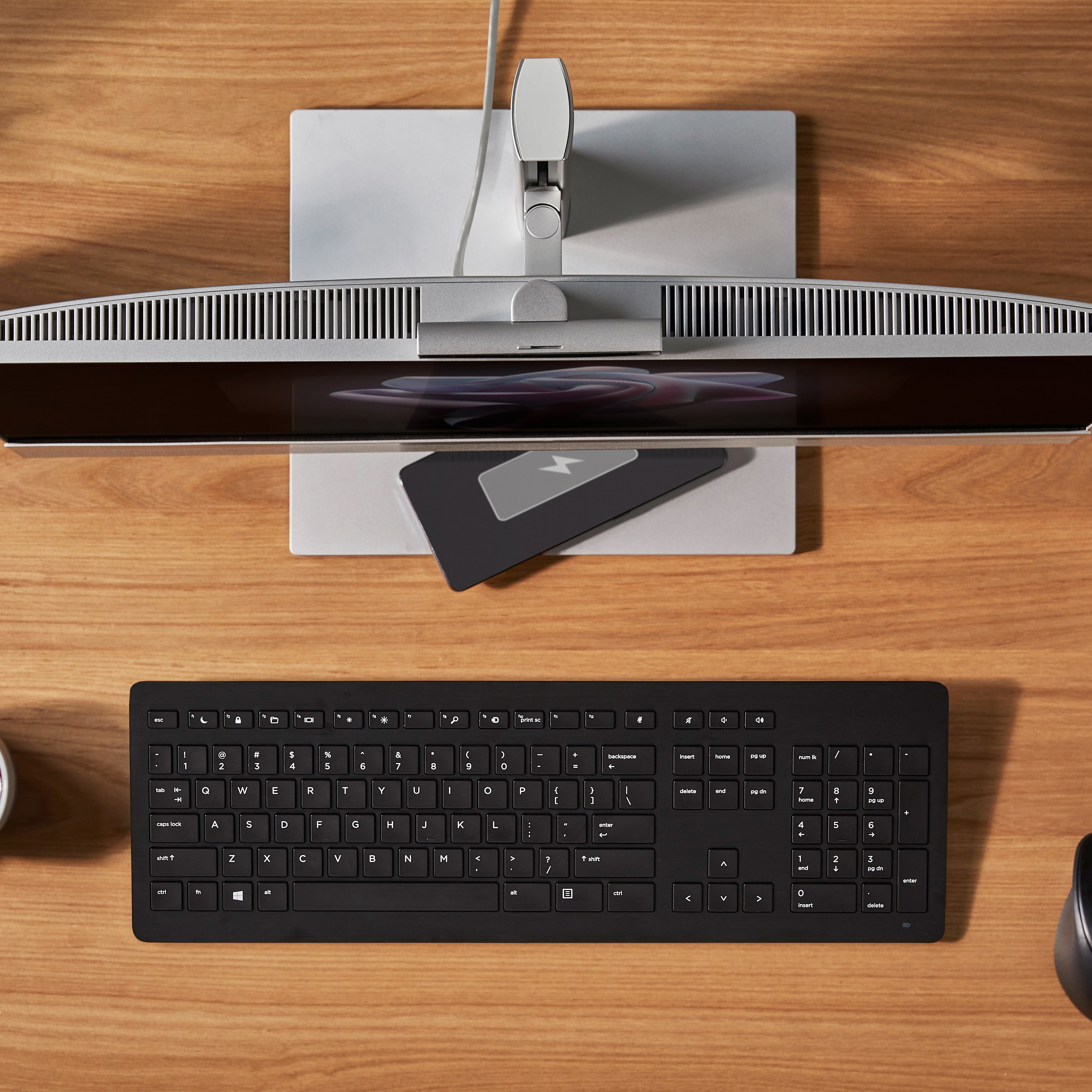 Ein schwarzes Keyboard und eine Computermaus auf einem Holztisch.