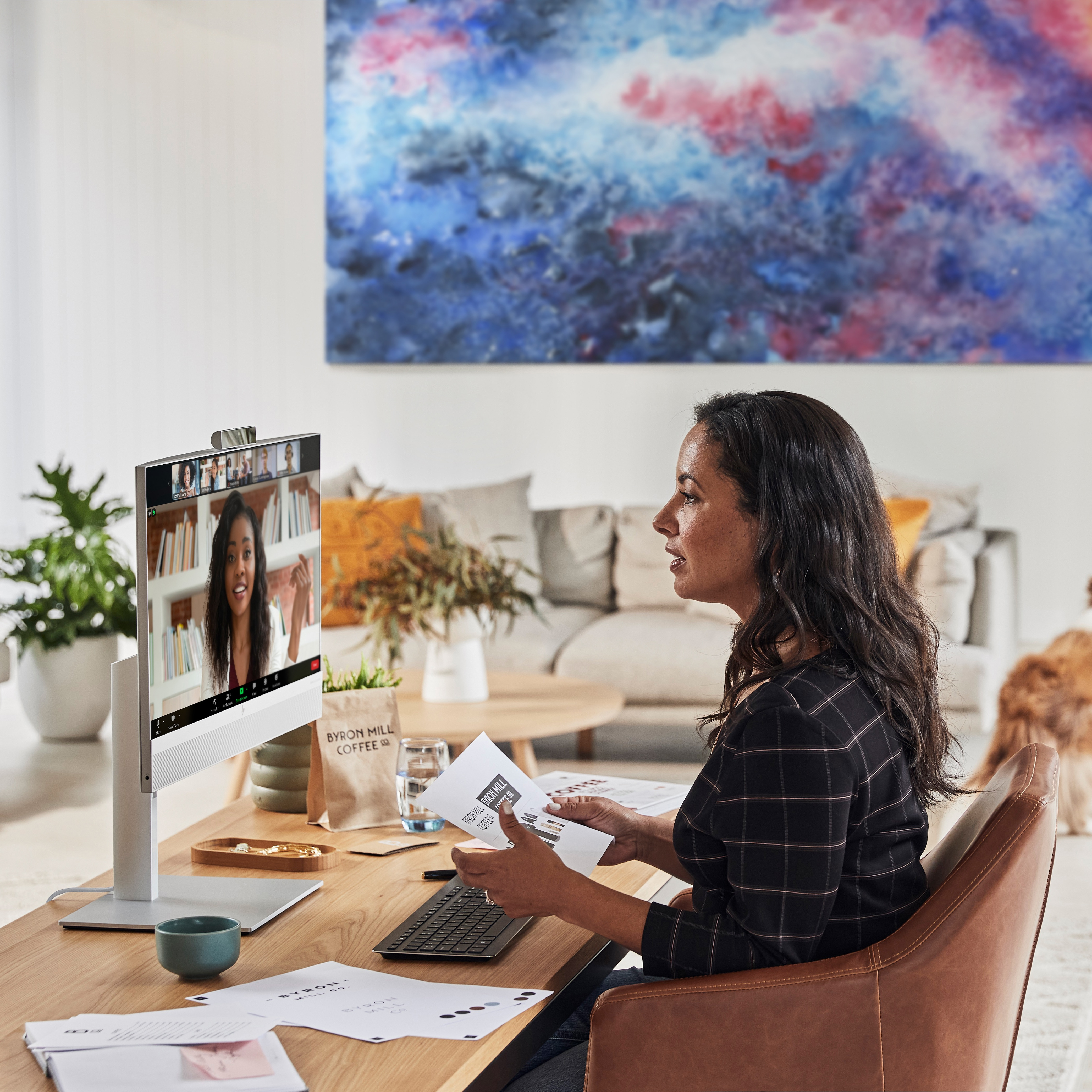 Frau in einem Büro mit einem Monitor, der einen Videoanruf zeigt.