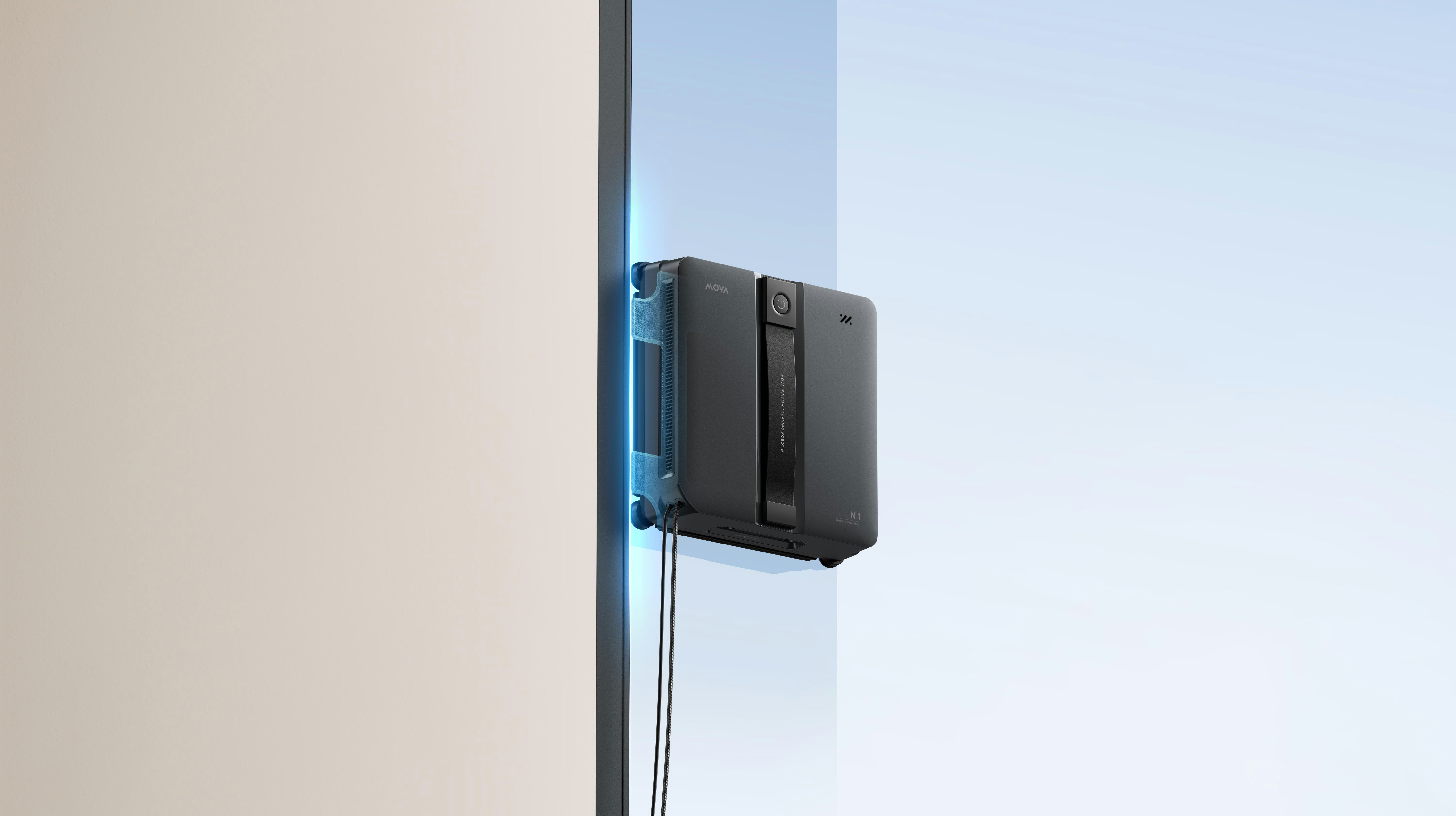 Ein schwarzer Fensterreinigungsroboter mit Kabeln haftet an einem Fenster.