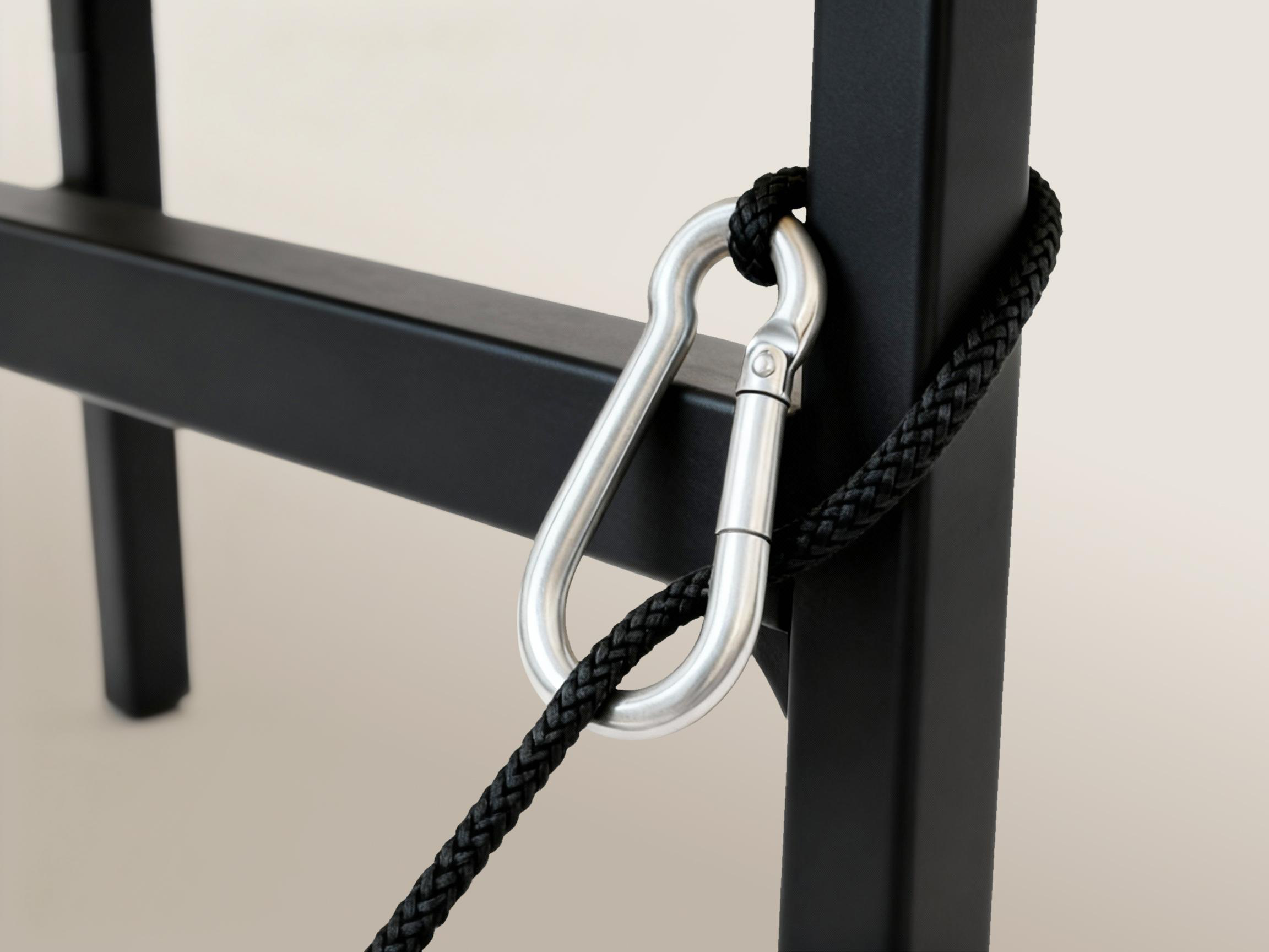 Ein Karabinerhaken befestigt ein schwarzes Seil an einem schwarzen Metallrahmen.