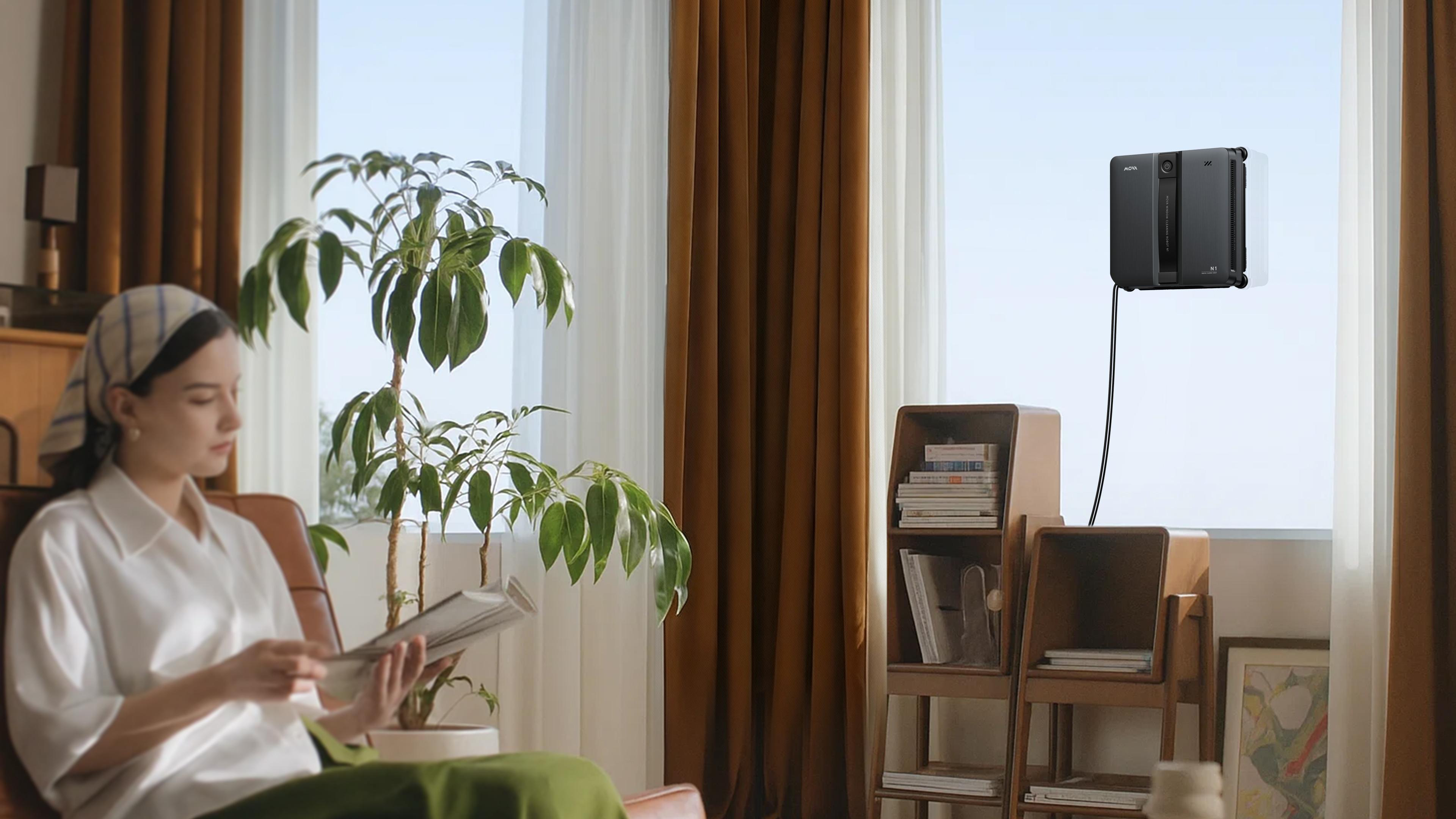 Ein Roboter-Fensterreiniger reinigt ein Fenster, während eine Frau im Sessel liest.
