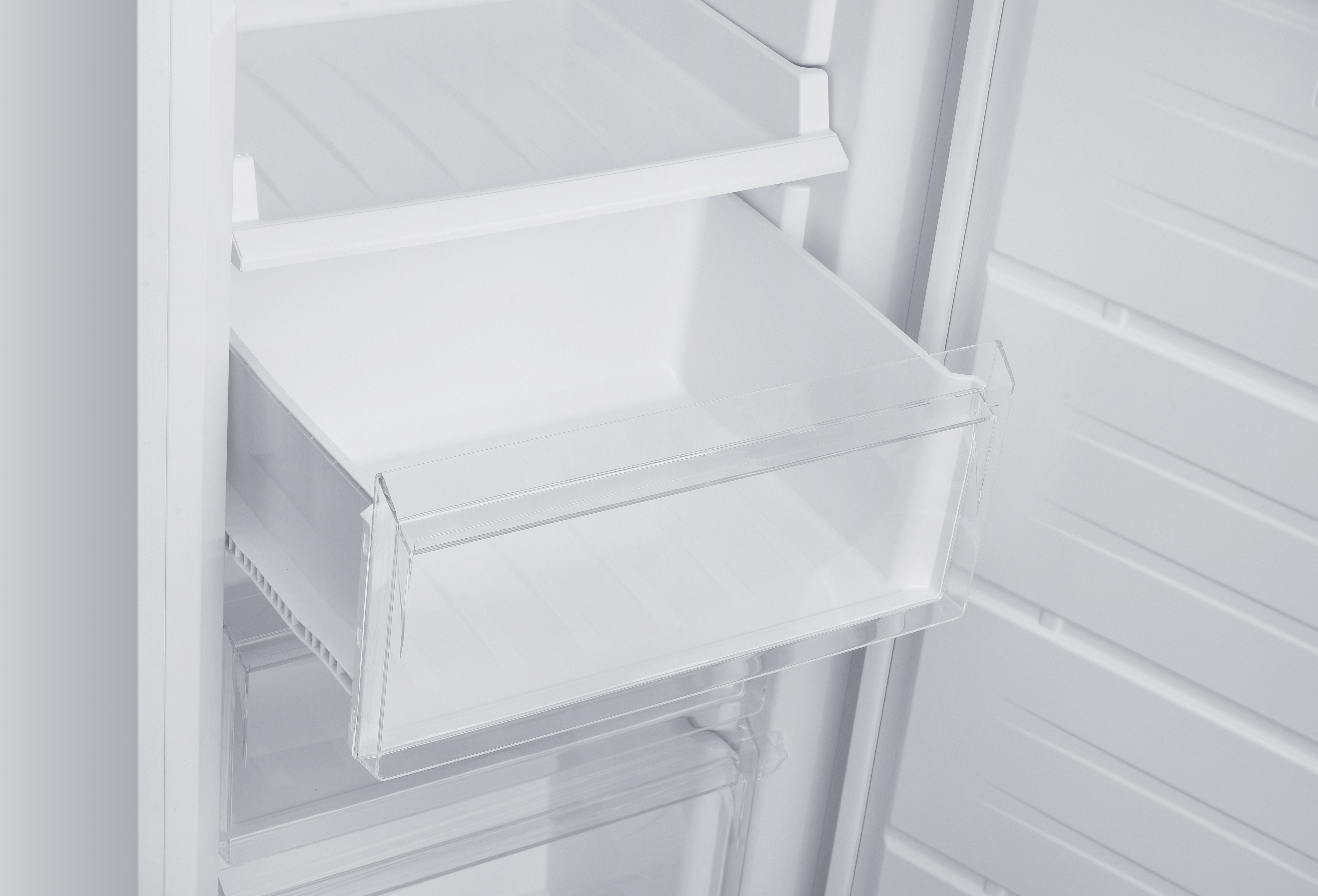Ein leerer Kühlschrank mit einem transparenten Fach in der Mitte.