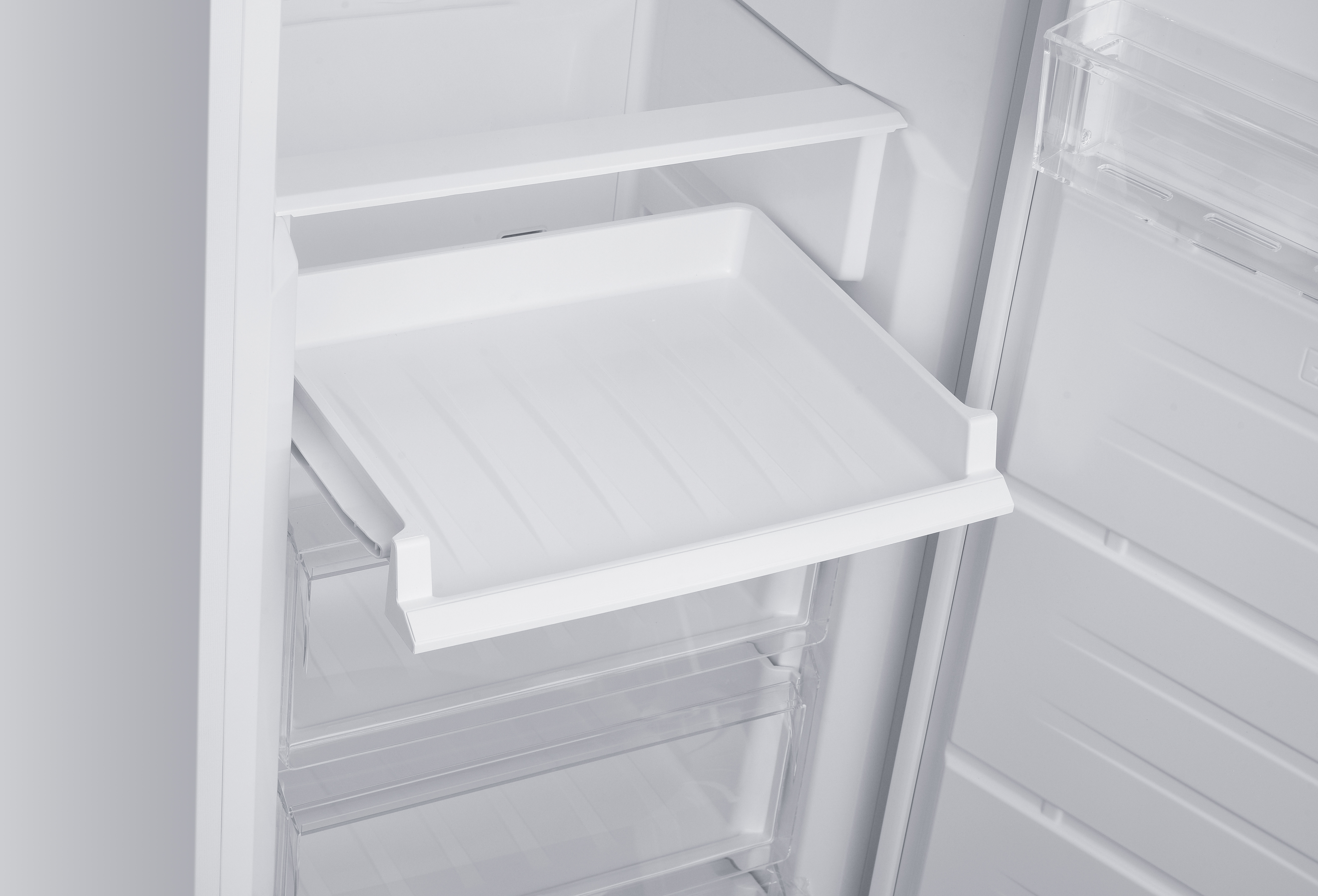 Ein weißer Kühlschrankinnenraum mit transparenten Schubladen und einem ausziehbaren Fach.
