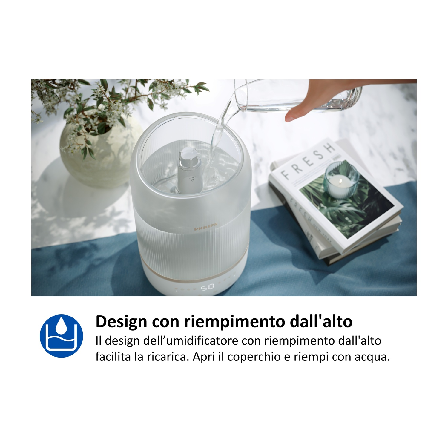Una mano versa acqua in un umidificatore bianco. Libri e fiori sono vicini.