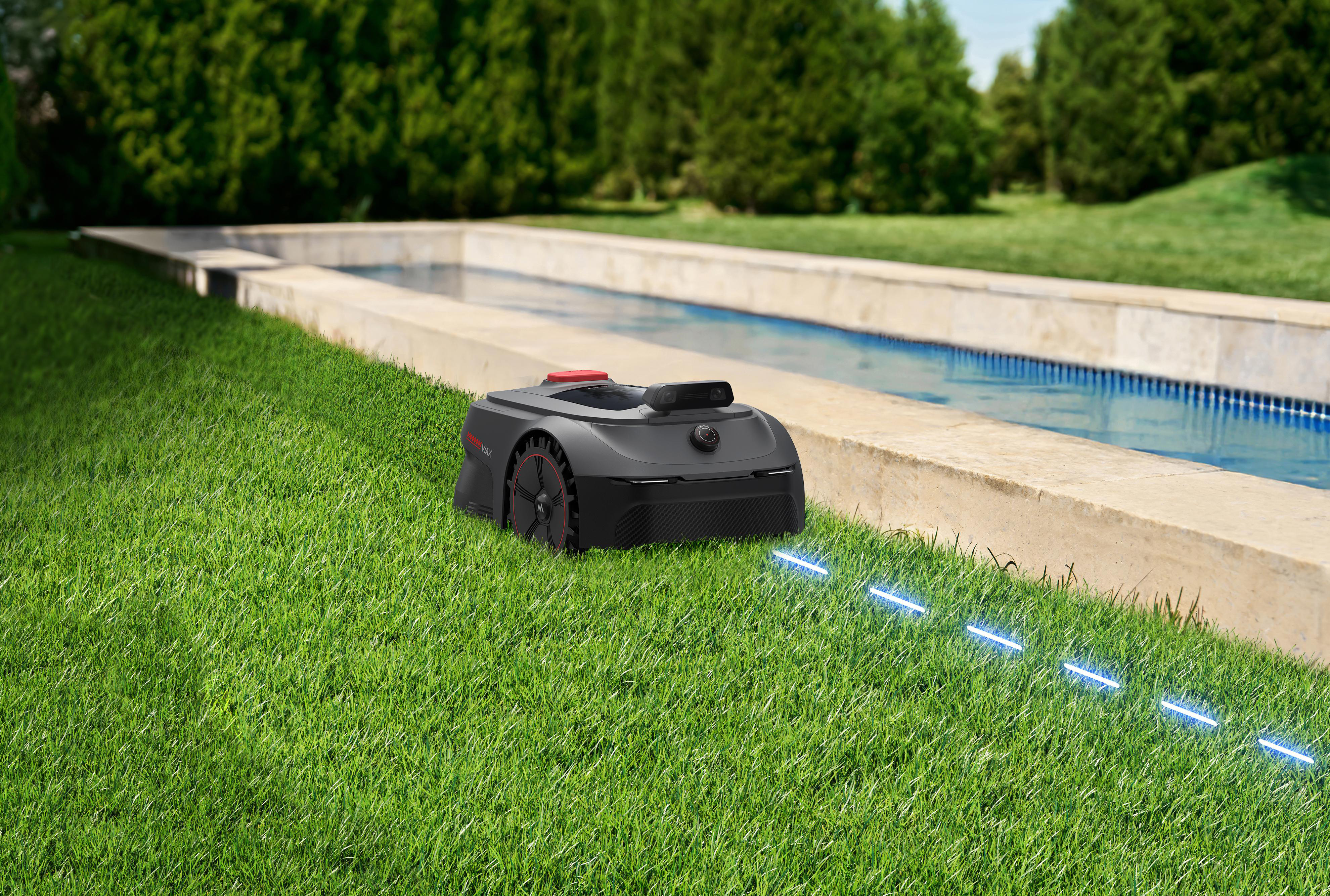 Ein schwarzer Mähroboter auf einem grünen Rasen neben einem Pool.