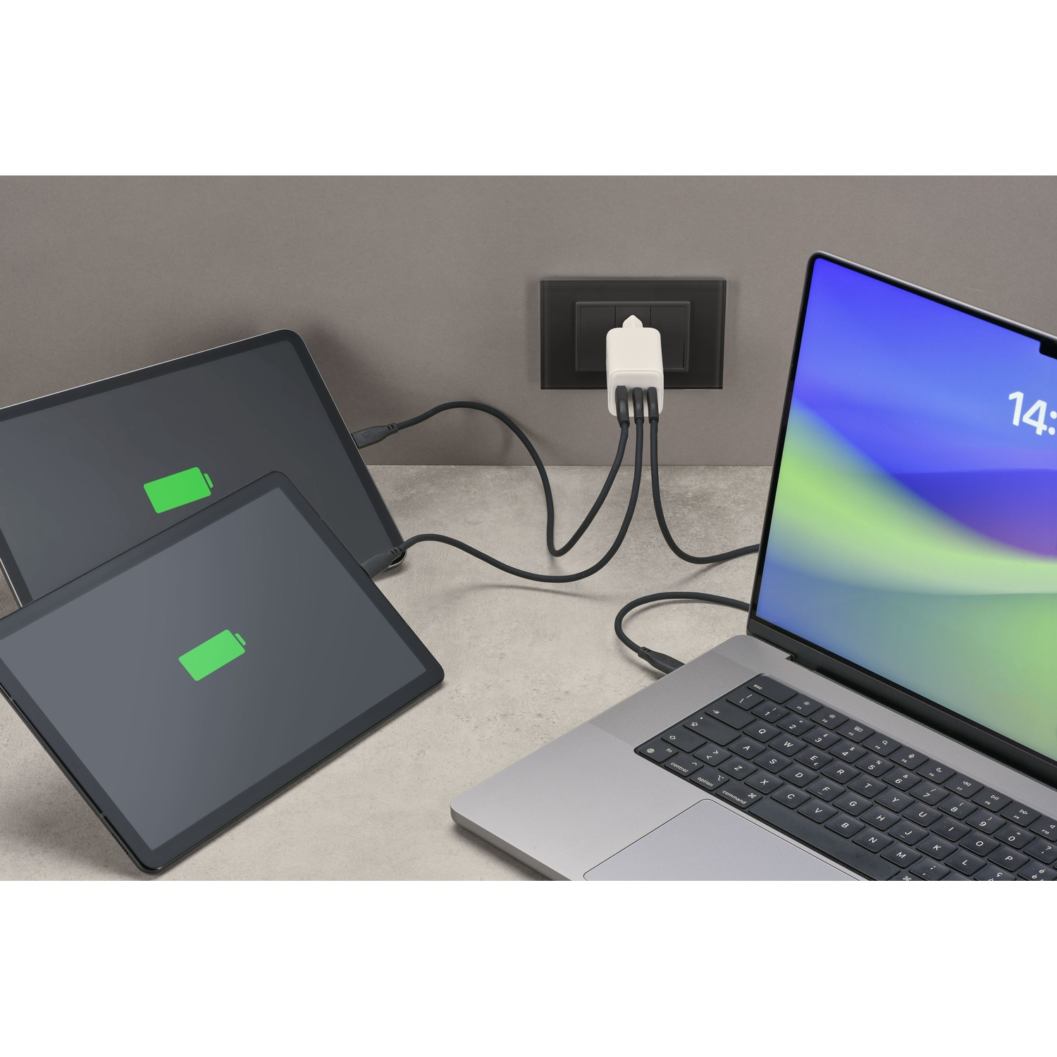 Un laptop e due tablet sono collegati a un caricabatterie multiport.