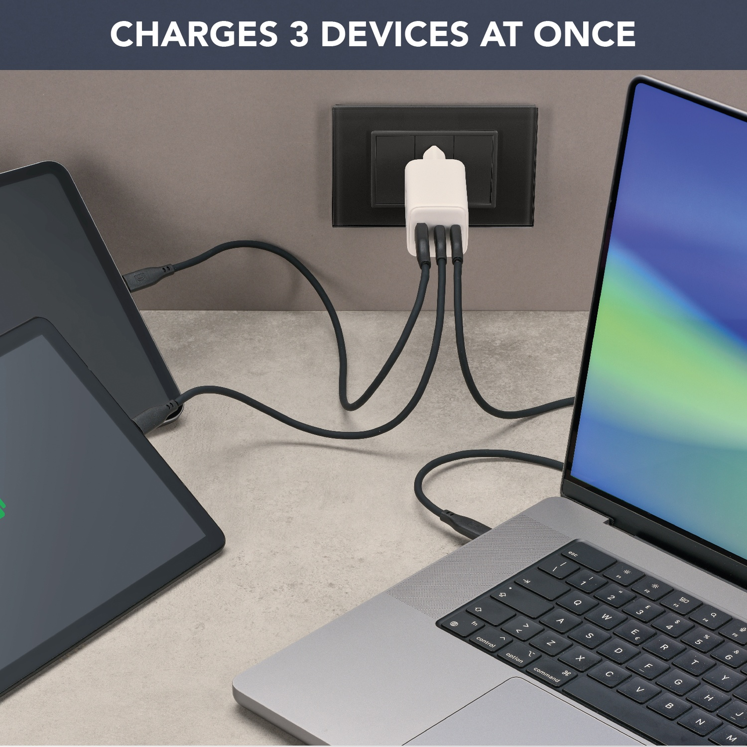 Un caricabatterie bianco con tre cavi neri collegati a un laptop e due tablet.