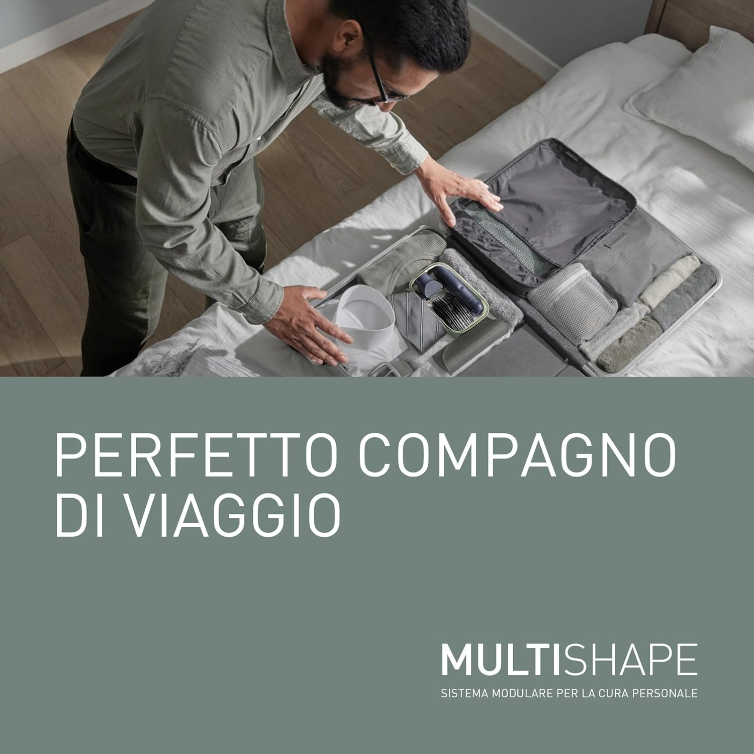 Uomo che sistema vestiti in una valigia, letto sullo sfondo.
