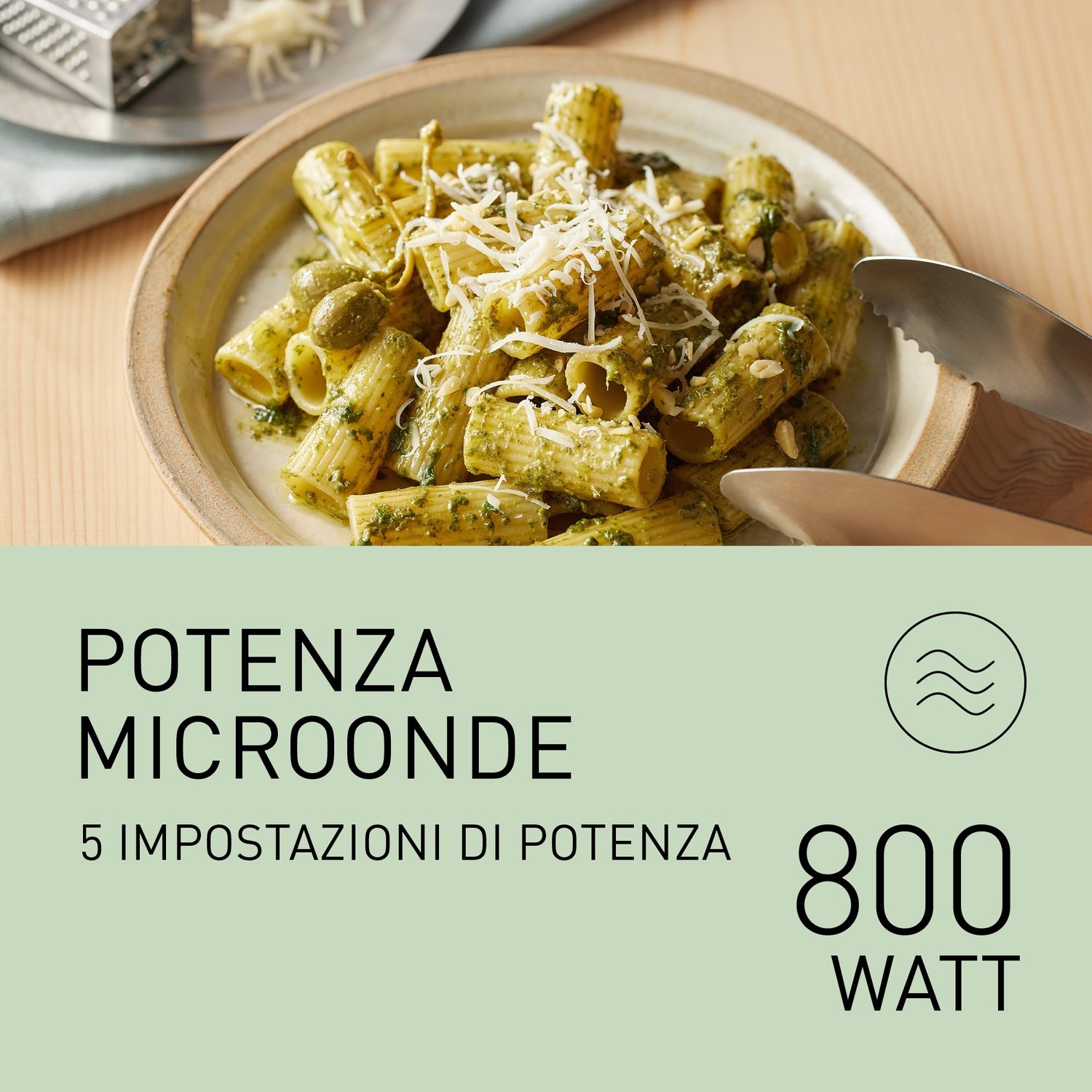 Un piatto di pasta rigatoni con pesto, olive e formaggio grattugiato.