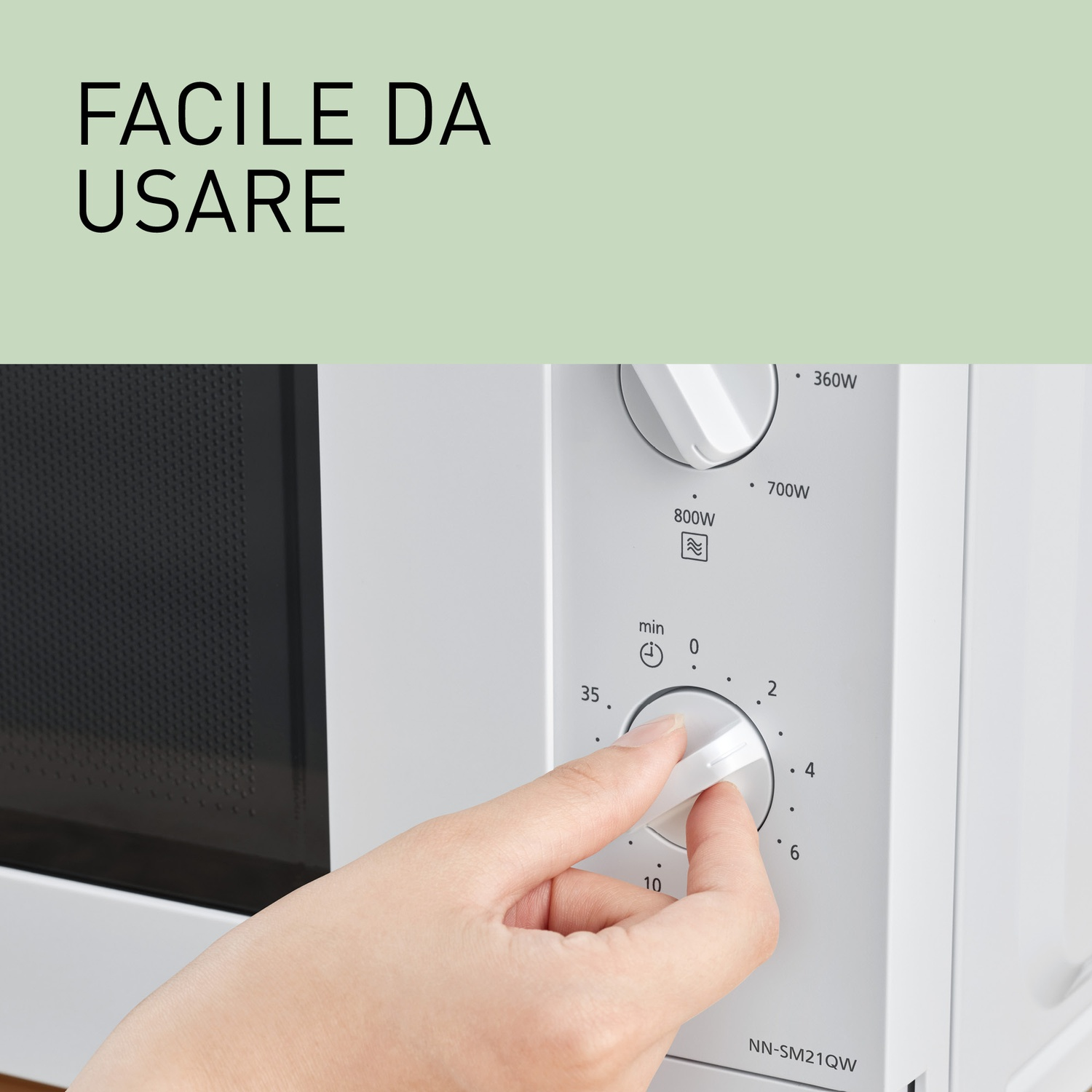 Una mano gira una manopola su un microonde bianco per impostare l'ora.