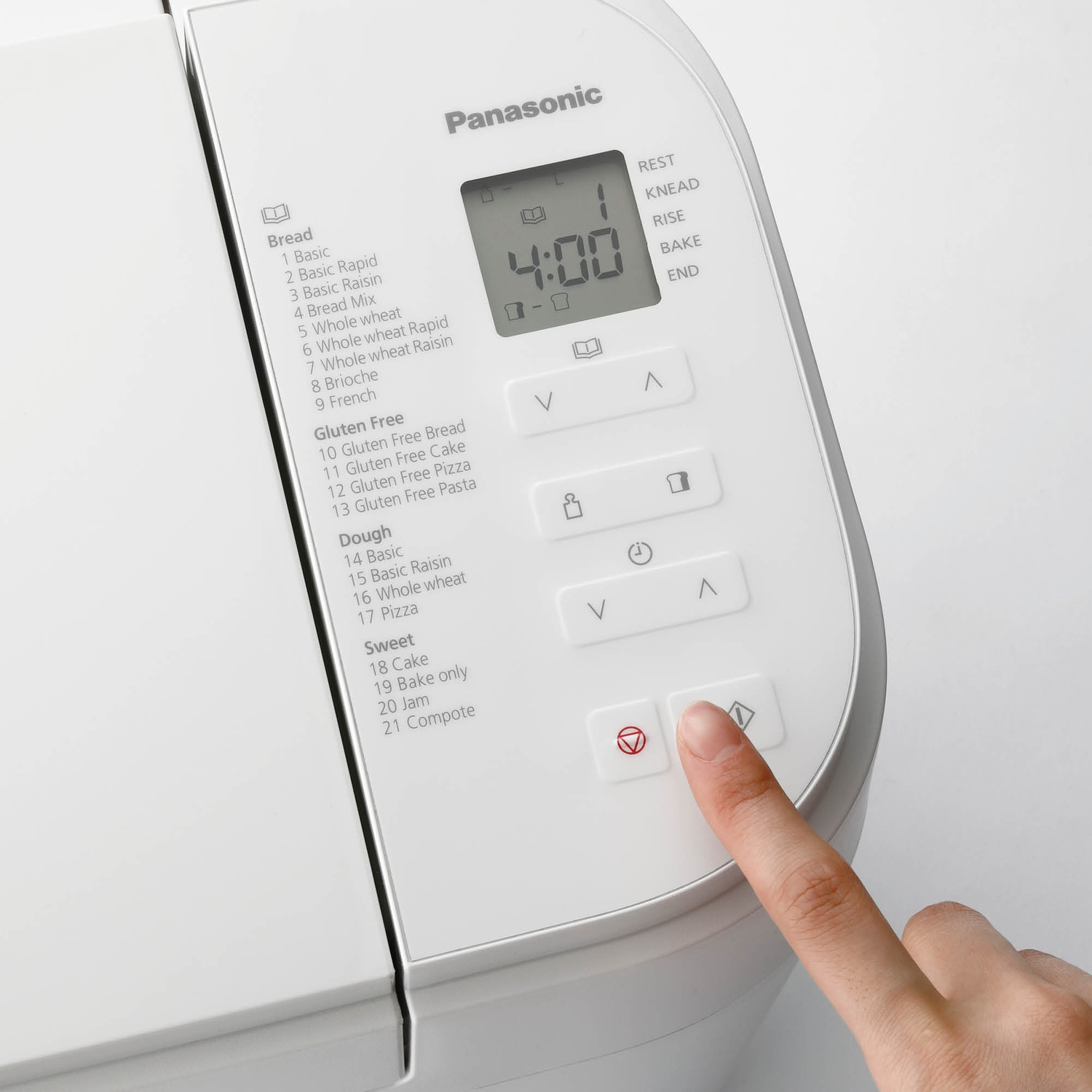 Una mano preme un pulsante su una macchina per il pane Panasonic bianca con display LCD.