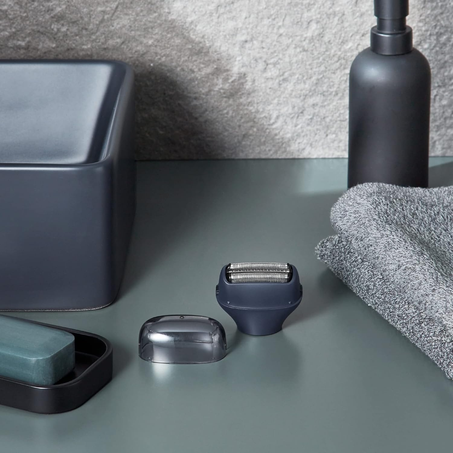 Set da bagno grigio scuro con sapone, rasoio, bottiglia e asciugamano.
