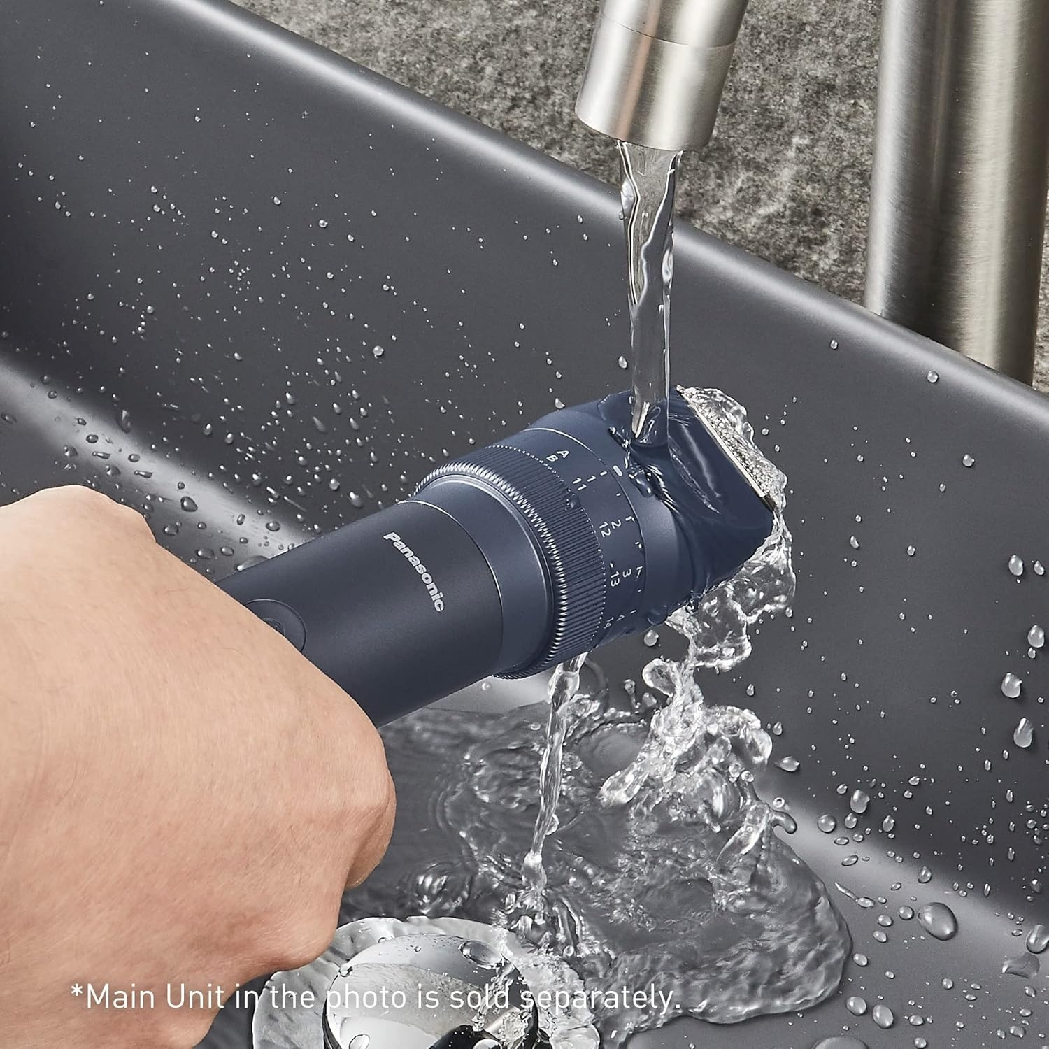 Un rifinitore Panasonic scuro viene sciacquato sotto acqua corrente in un lavandino.