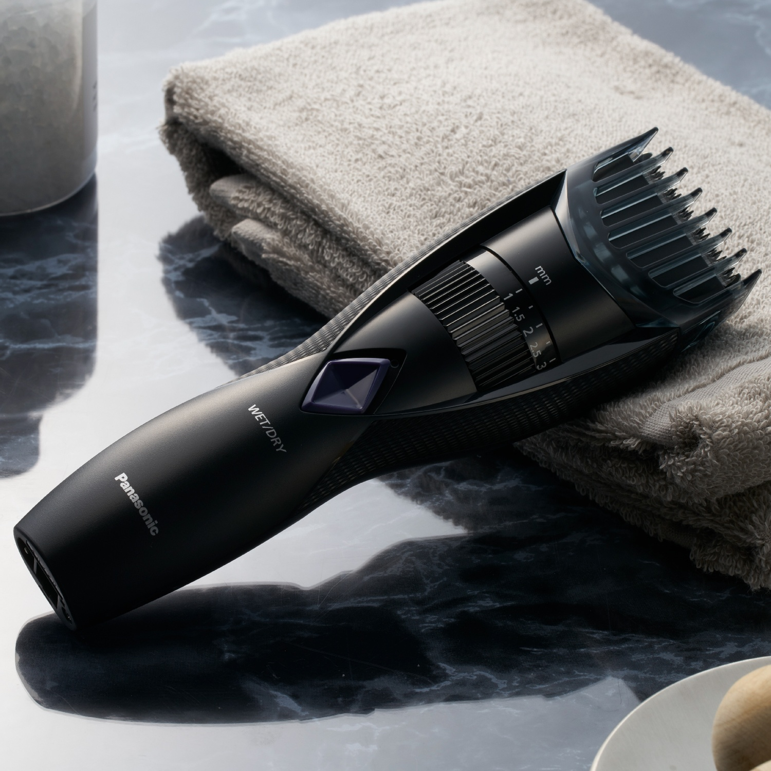 Regolabarba Panasonic nero con accessorio su asciugamano grigio.