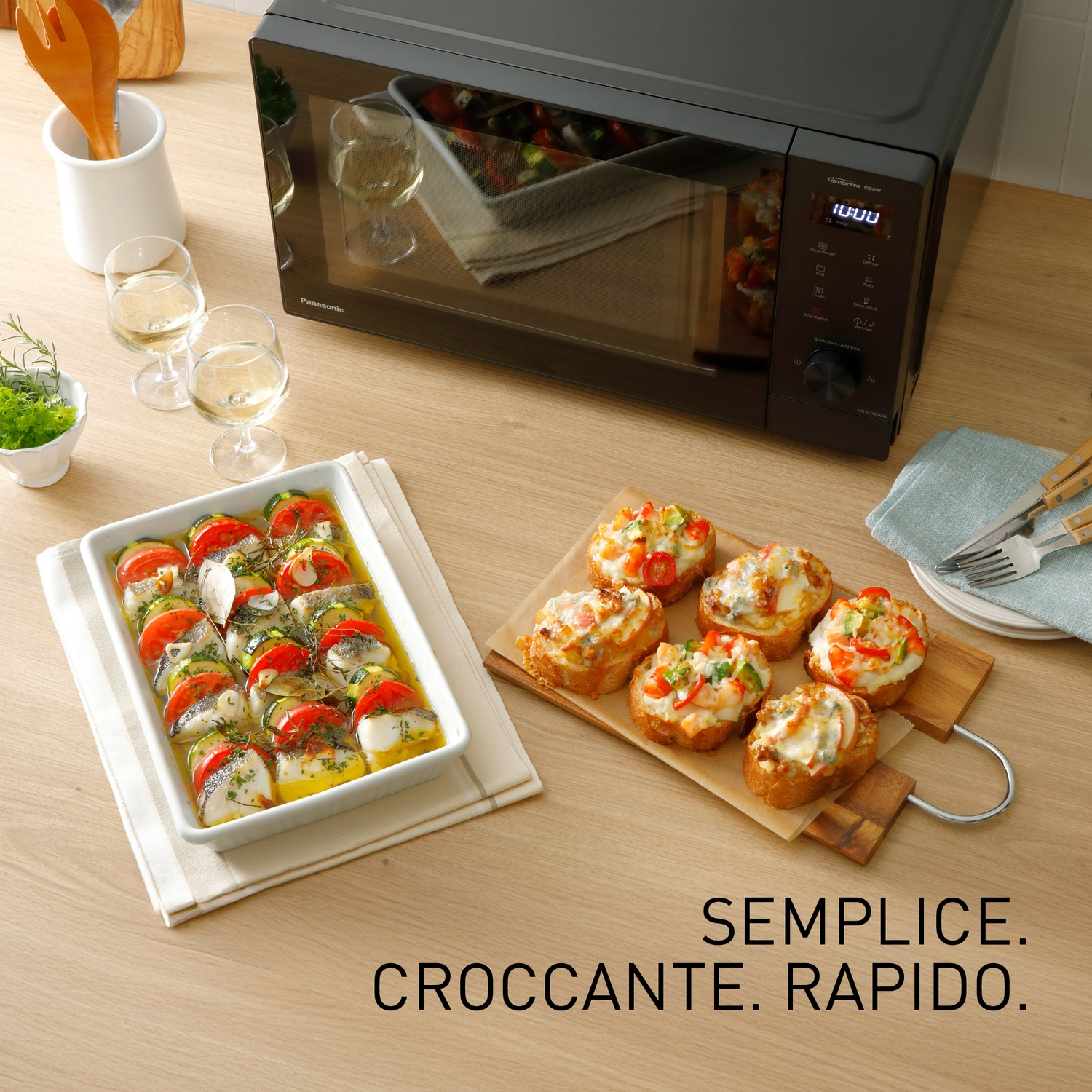 Forno a microonde con cibo, vino e bruschetta su un tavolo di legno.