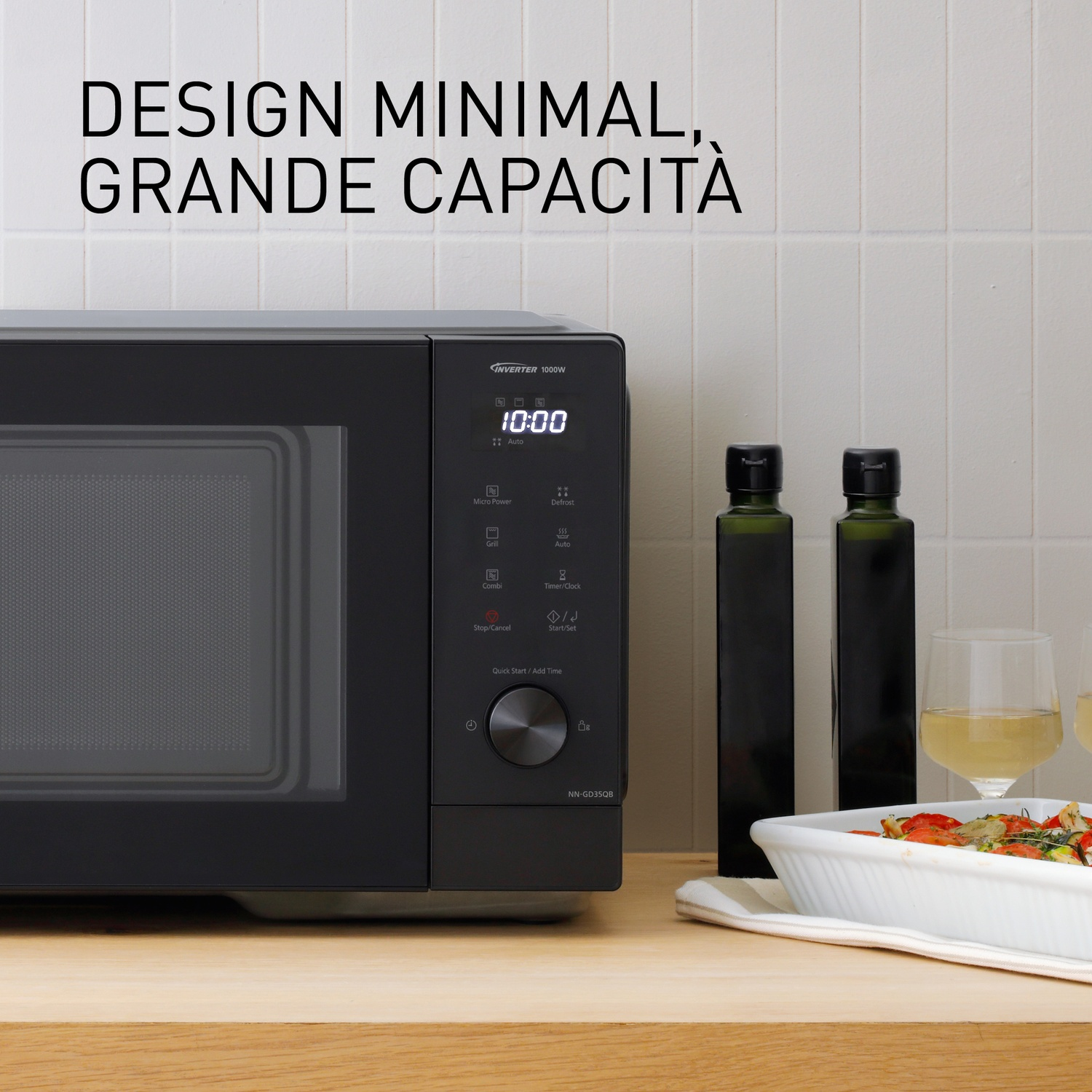 Forno a microonde nero con pannello di controllo, due bottiglie d'olio e calici.