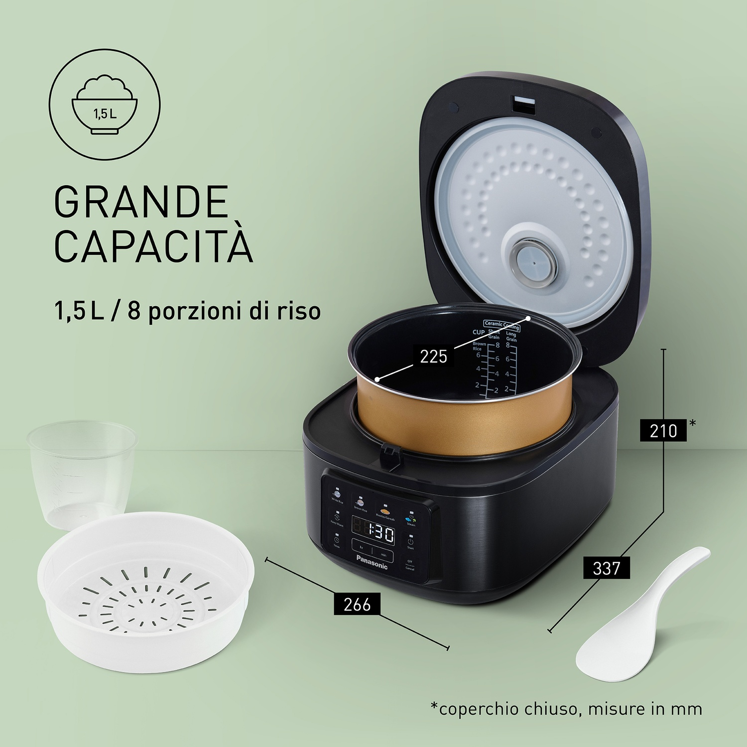 Una pentola per riso nera con coperchio aperto, accanto a misurino e cestello per vapore.