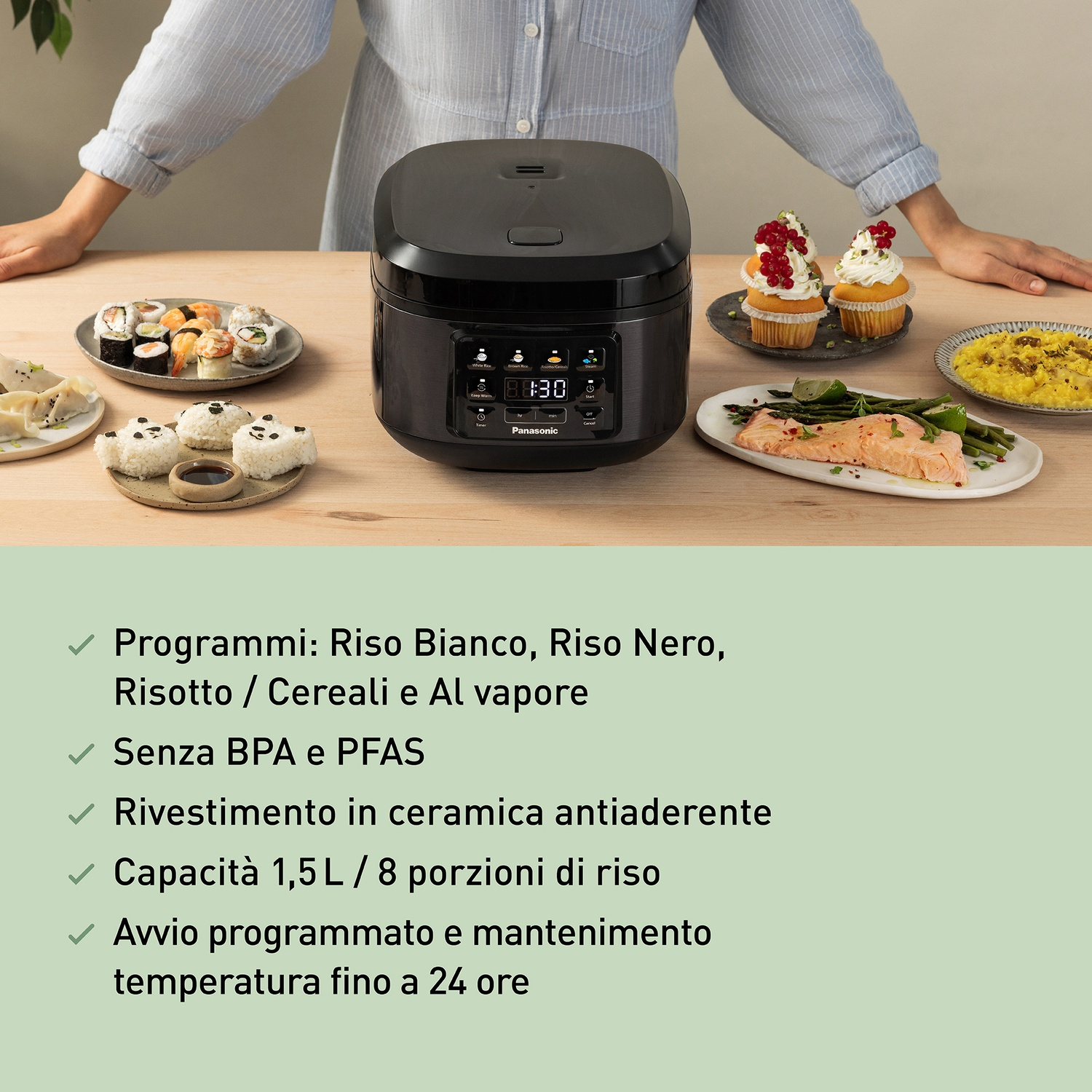 Una pentola per riso nera è su un tavolo di legno con sushi, cupcake e salmone.