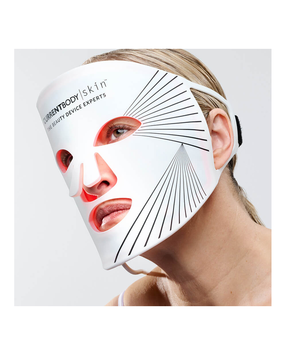 Una mujer lleva una mascarilla facial LED blanca con luces rojas.