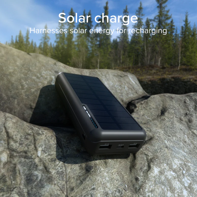 Ein schwarzes Solar-Ladegerät liegt auf Felsen, Bäume im Hintergrund.
