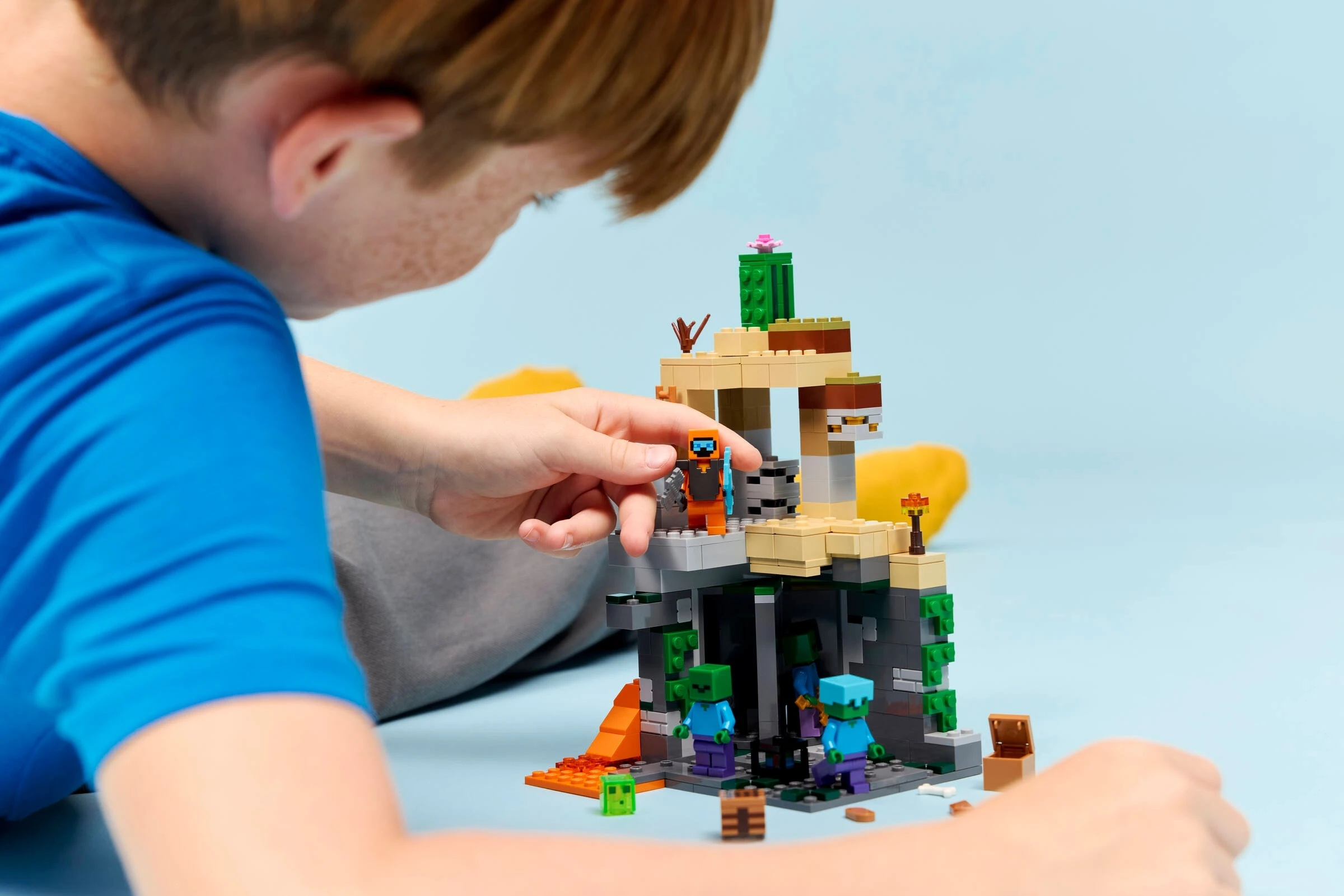 Chłopiec bawi się figurkami Lego, budując scenę z Minecrafta z zombie.