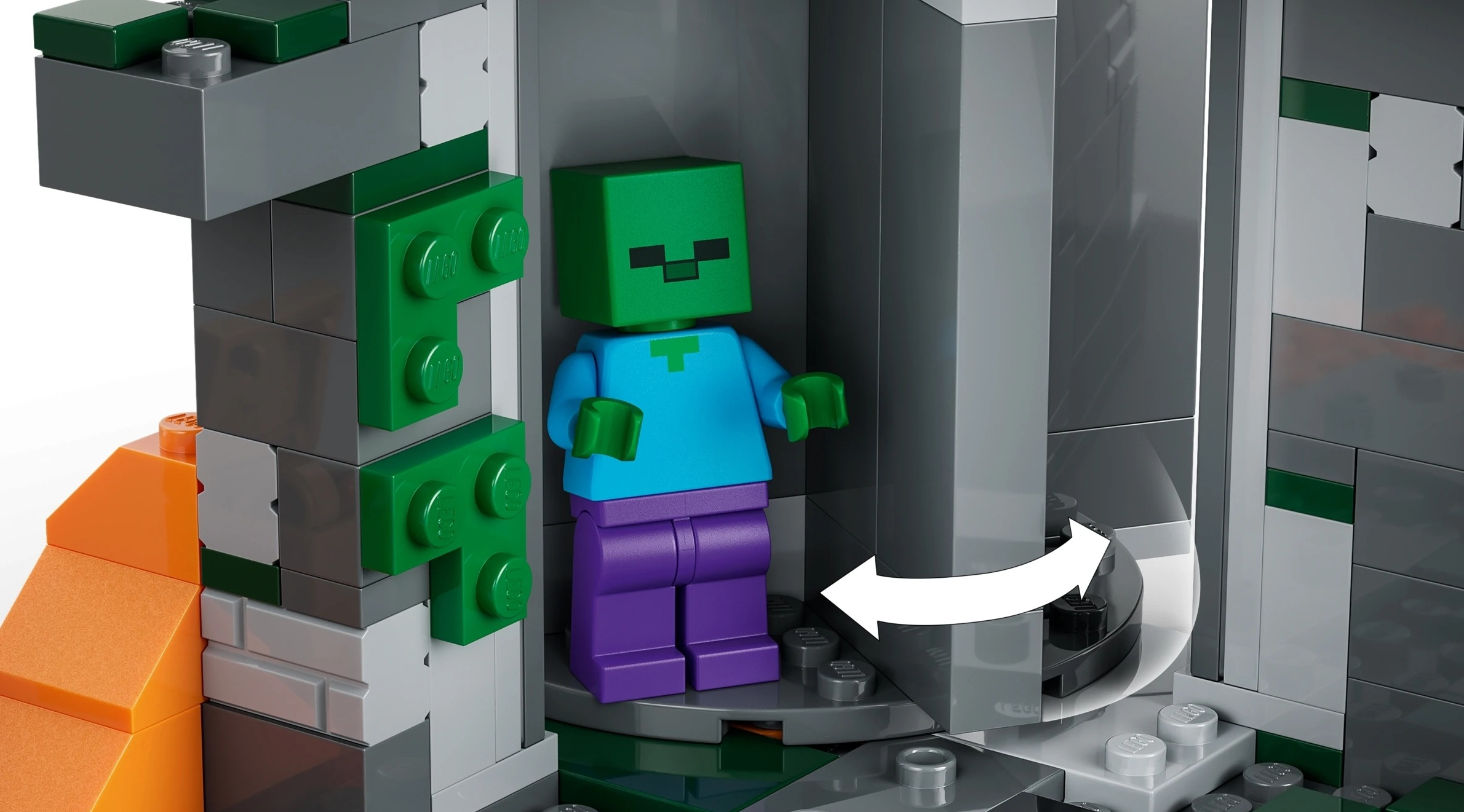 Zielony zombie Lego w niebieskiej bluzce i fioletowych spodniach stoi w szarej konstrukcji Lego.