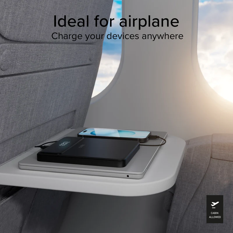 Ein Laptop, eine Powerbank und ein Smartphone laden auf einem Flugzeugklapptisch.