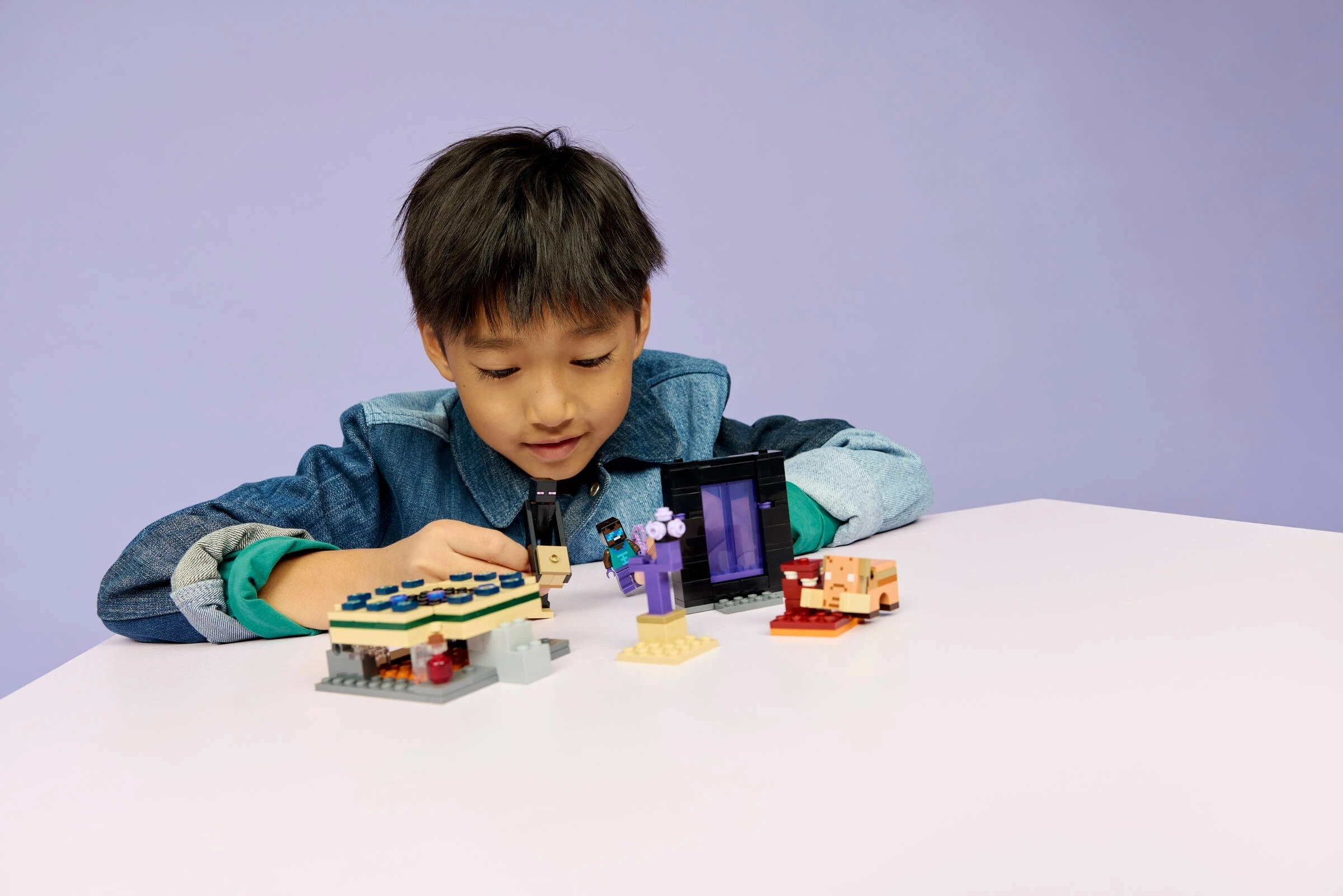 Chłopiec bawi się klockami Lego Minecraft: portal, figurki i świnka.