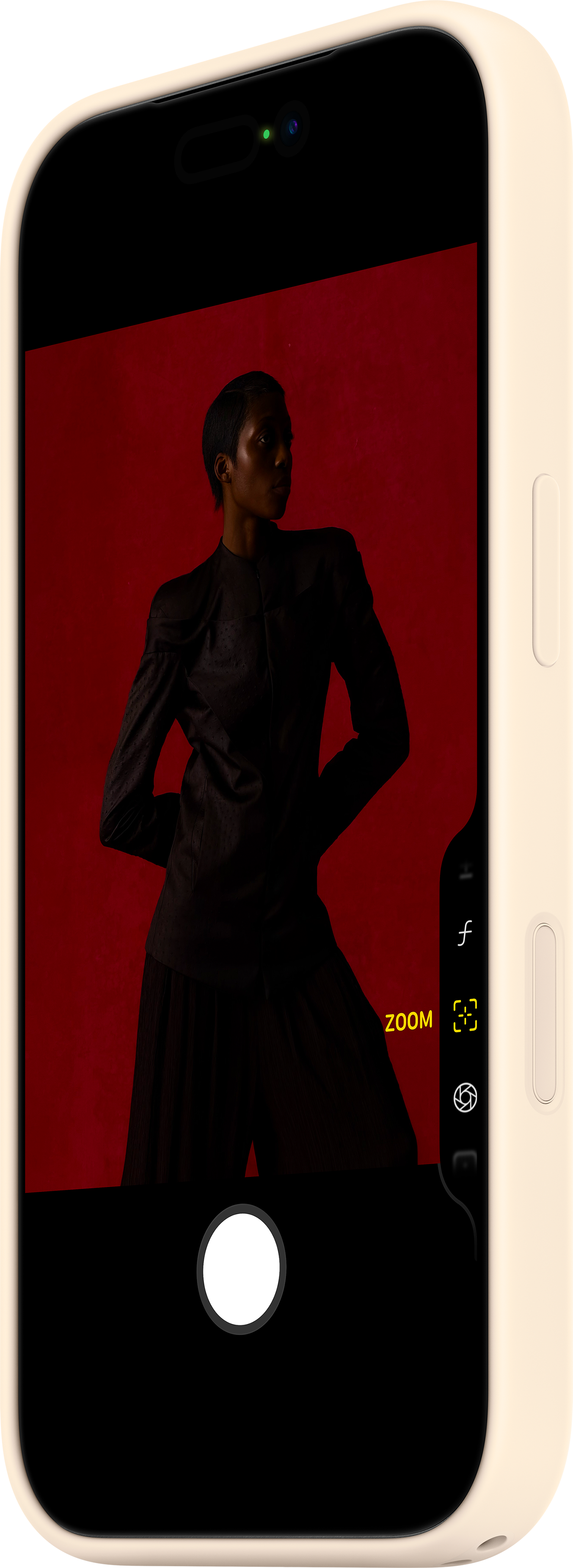 Una persona in abiti scuri posa su sfondo rosso, visualizzata su schermo di smartphone.