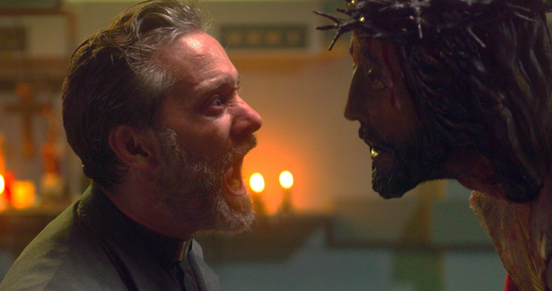 Ein Mann mit Bart schreit eine Jesus-Statue mit Dornenkrone an.