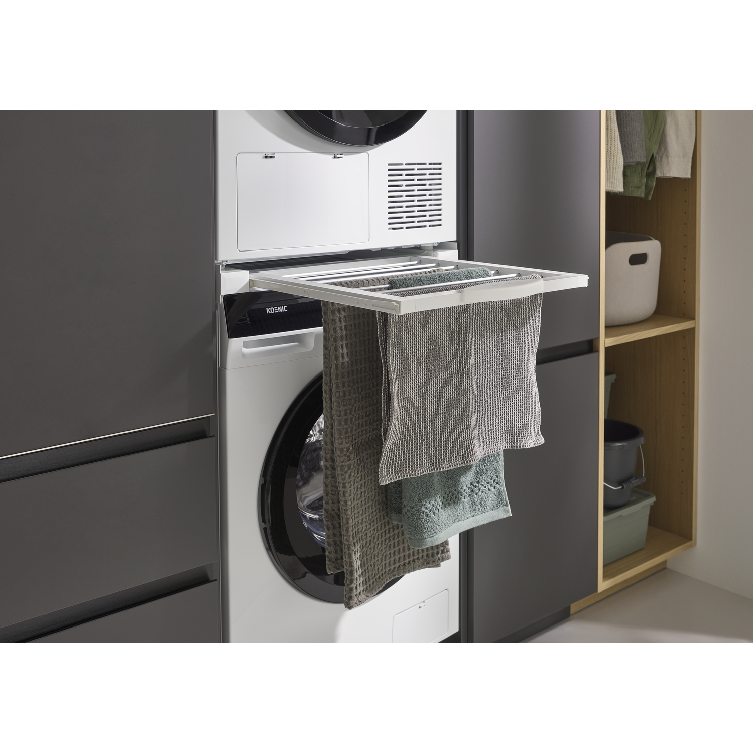 A drying rack with towels hangs over a washing machine.