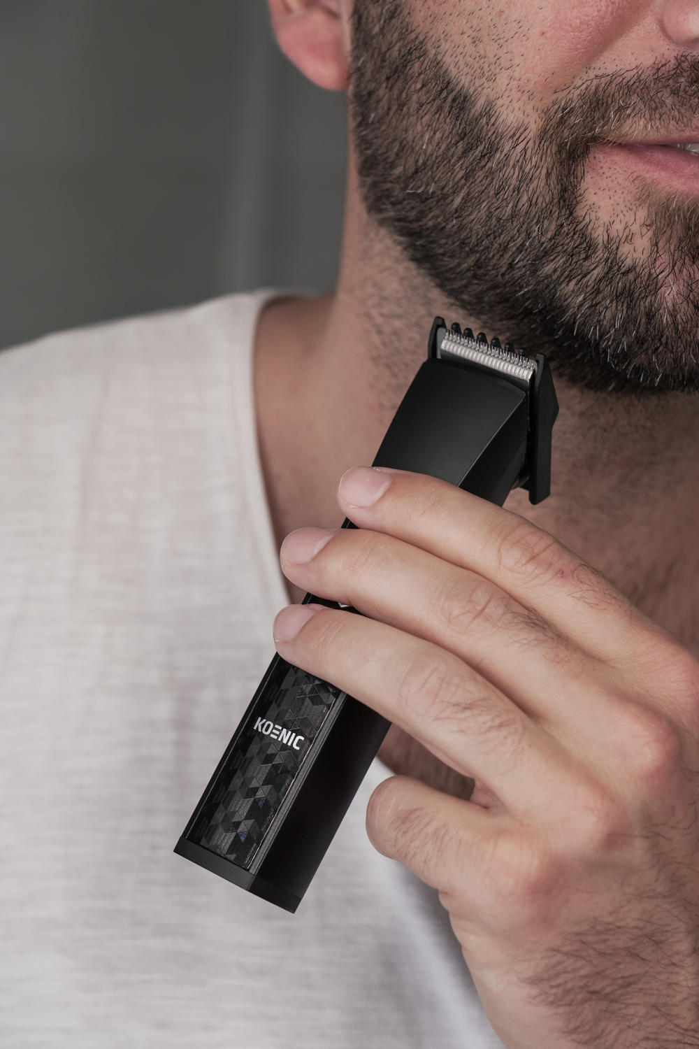 Un hombre se recorta la barba con una recortadora negra.