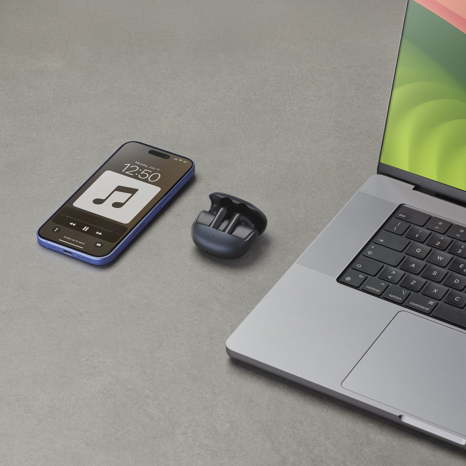 Un iPhone blu mostra app musicale, vicino a auricolari wireless scuri e laptop argento.