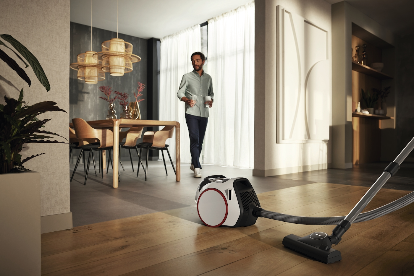 Ein Mann geht an einem weißen Staubsauger vorbei in einem modernen Esszimmer.