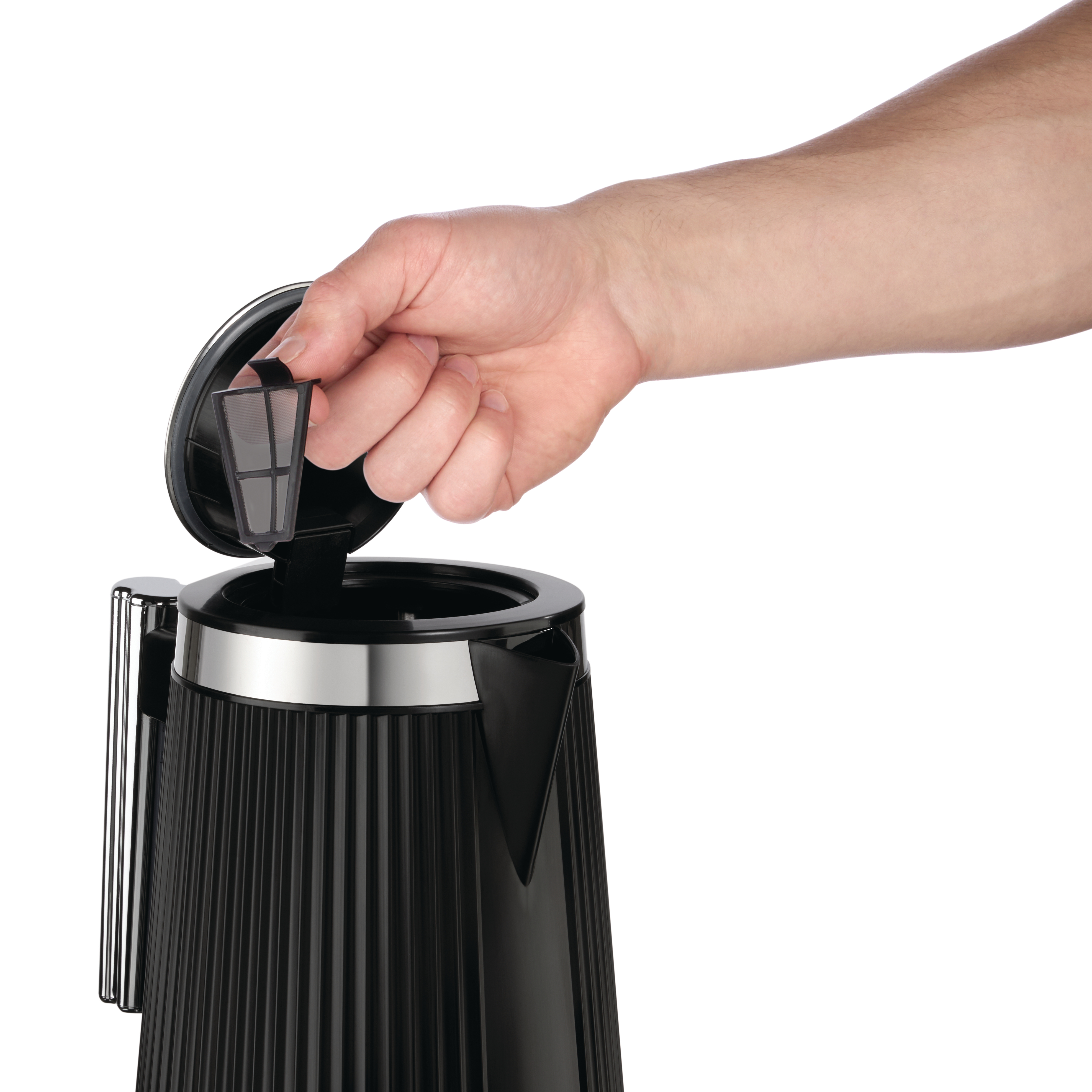 Hand setzt einen schwarzen Teefilter in einen schwarzen Wasserkocher ein.