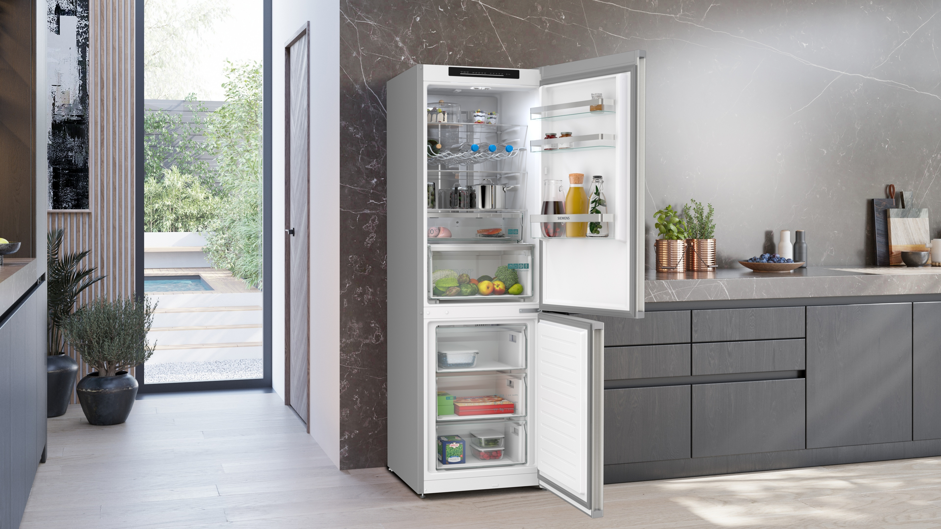 Ein offener Kühlschrank steht in einer modernen Küche mit Marmor-Arbeitsplatte und Blick nach draußen.