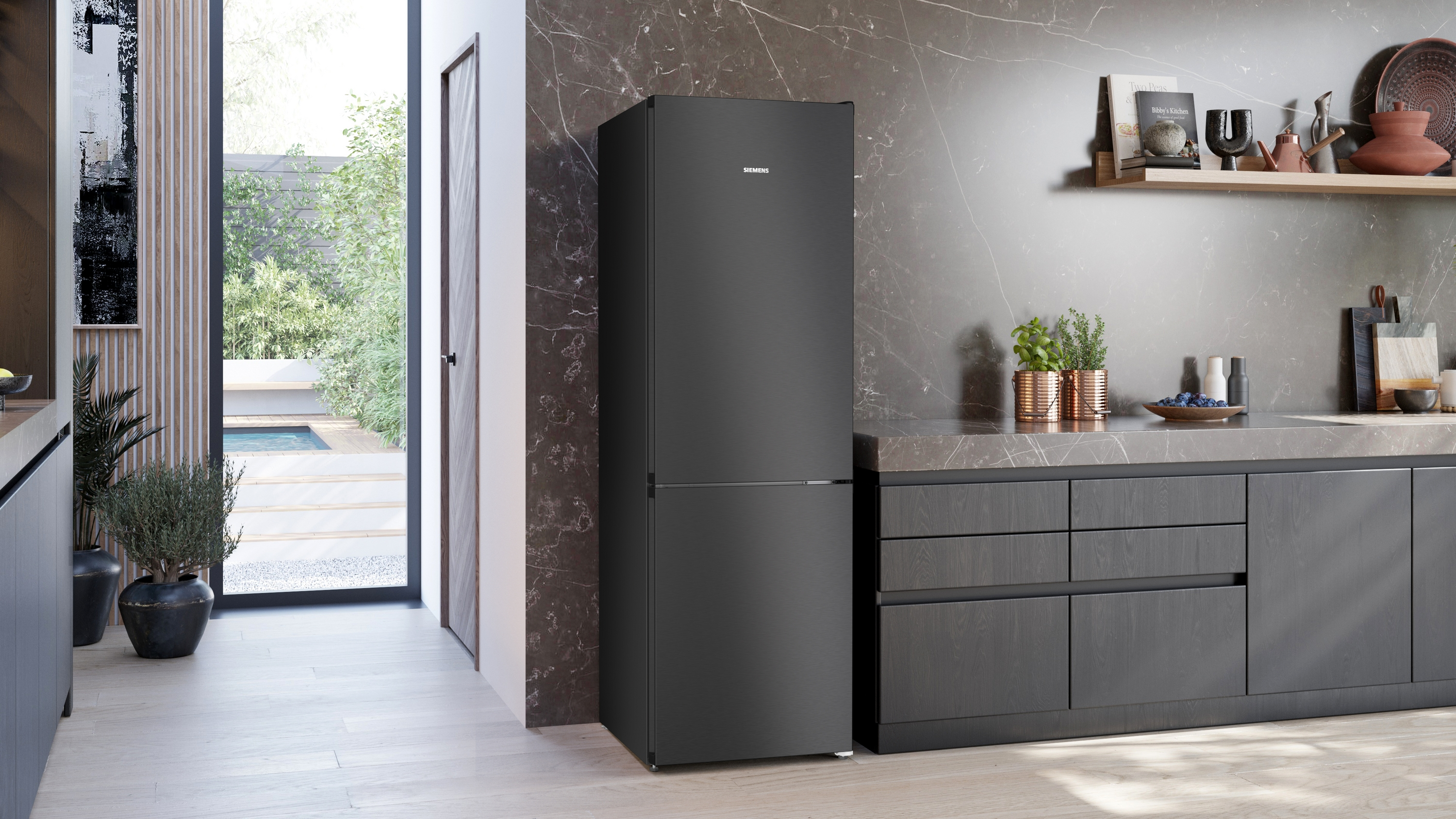 Ein schwarzer Kühlschrank steht in einer modernen Küche mit Marmorrückwand.