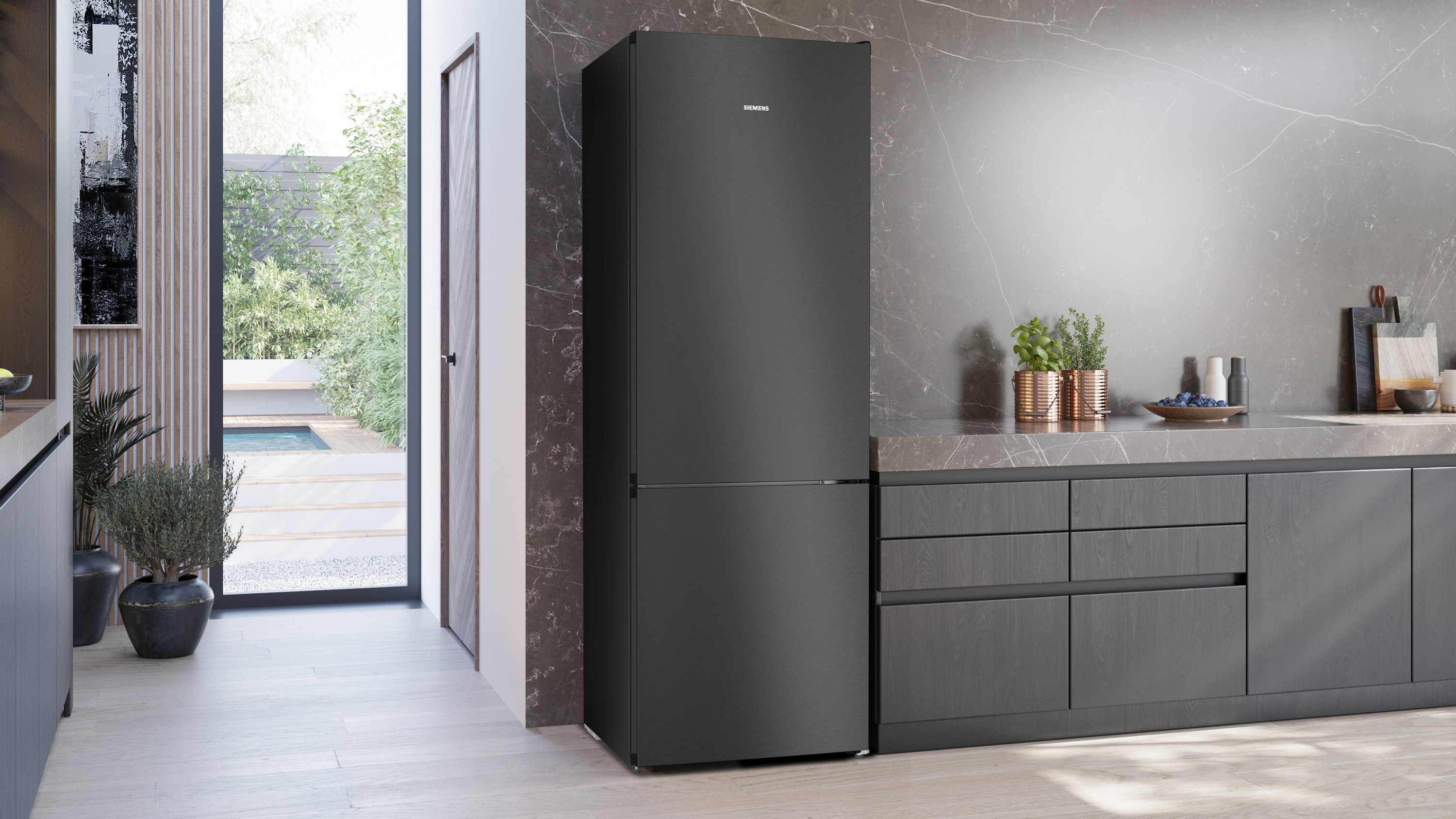 Ein schwarzer Kühlschrank steht in einer modernen Küche mit Marmorarbeitsplatte.