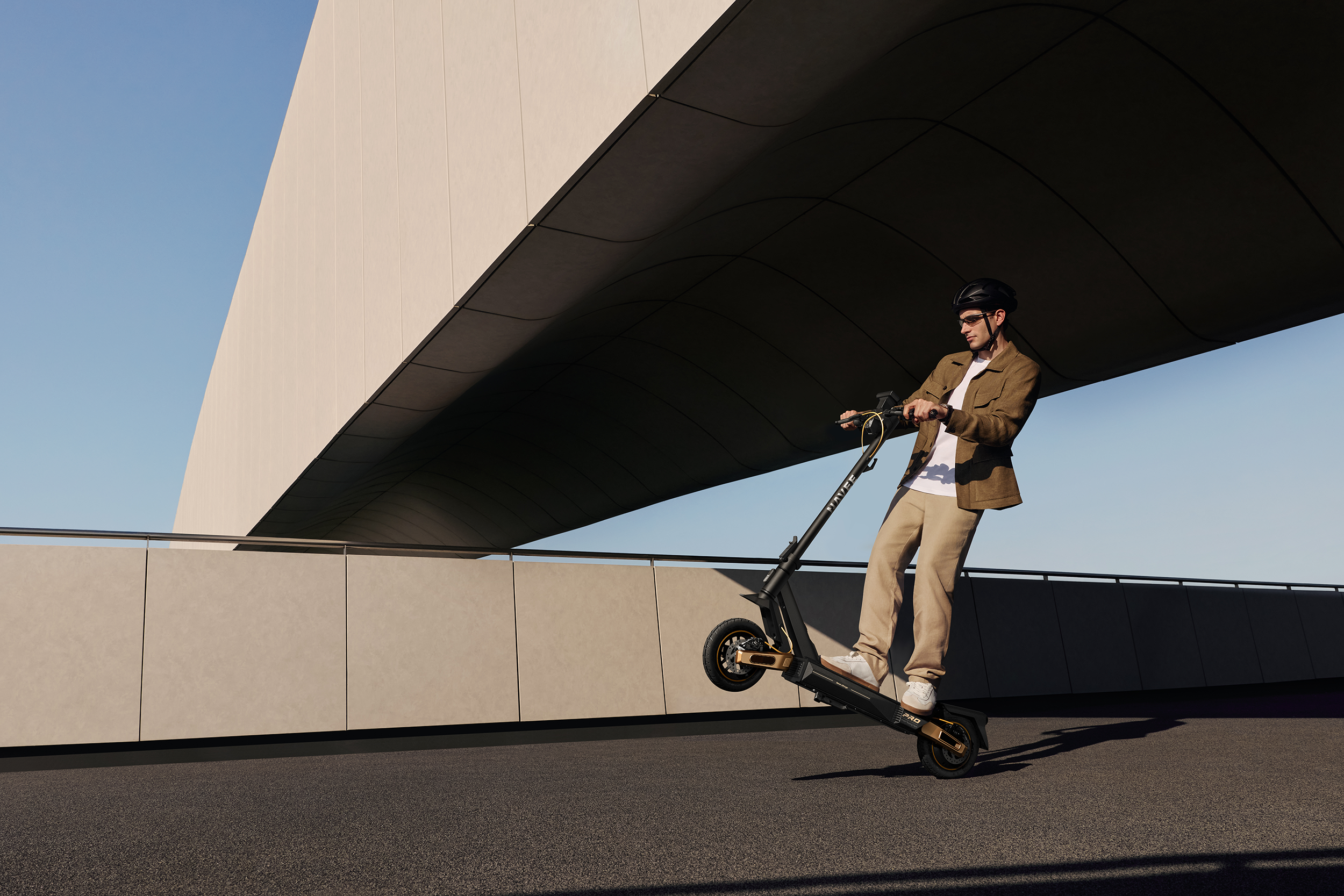 Mann mit Helm fährt E-Scooter unter einem modernen Gebäude.