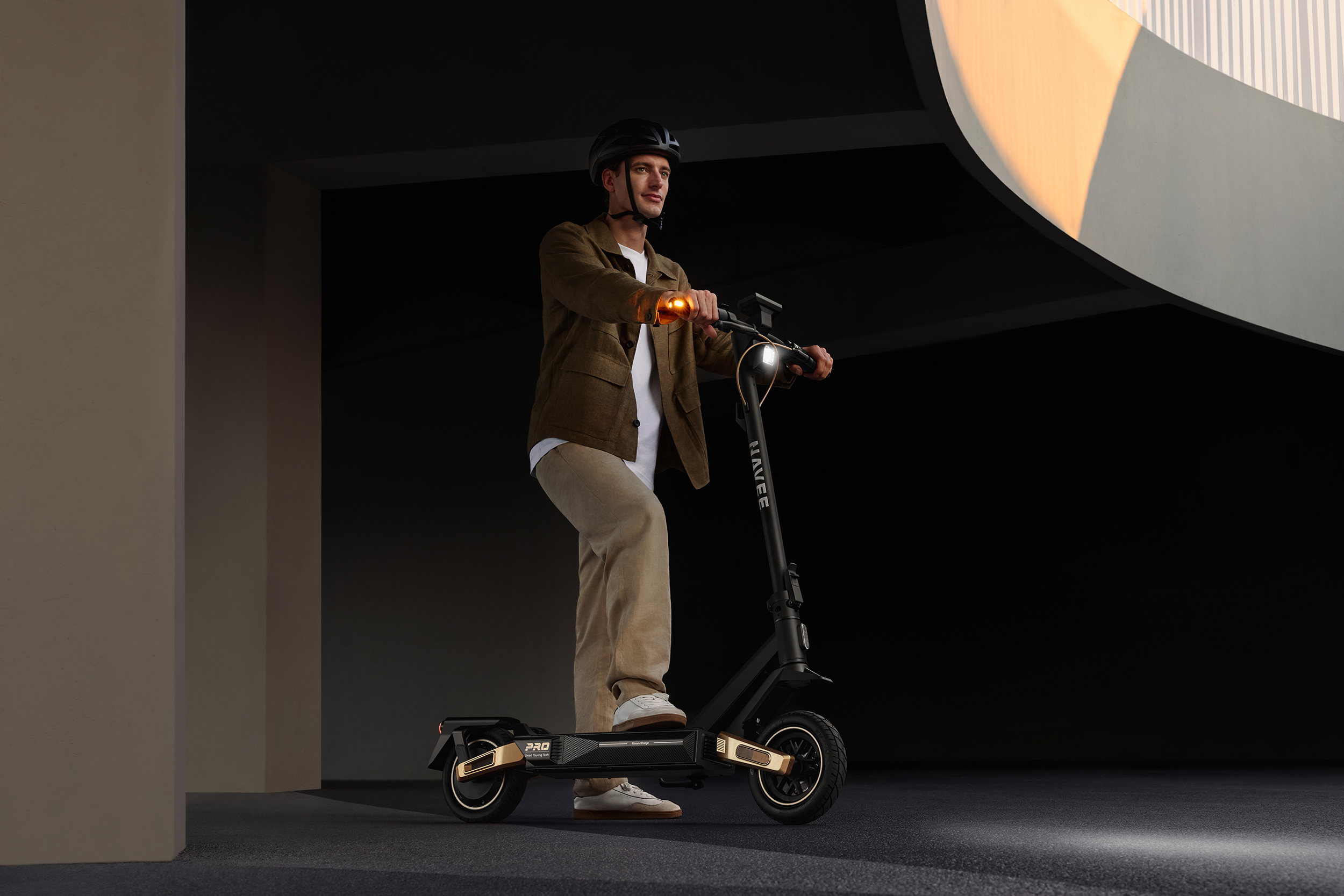 Mann mit Helm fährt E-Scooter mit orangefarbenen Lichtern in dunkler Umgebung.