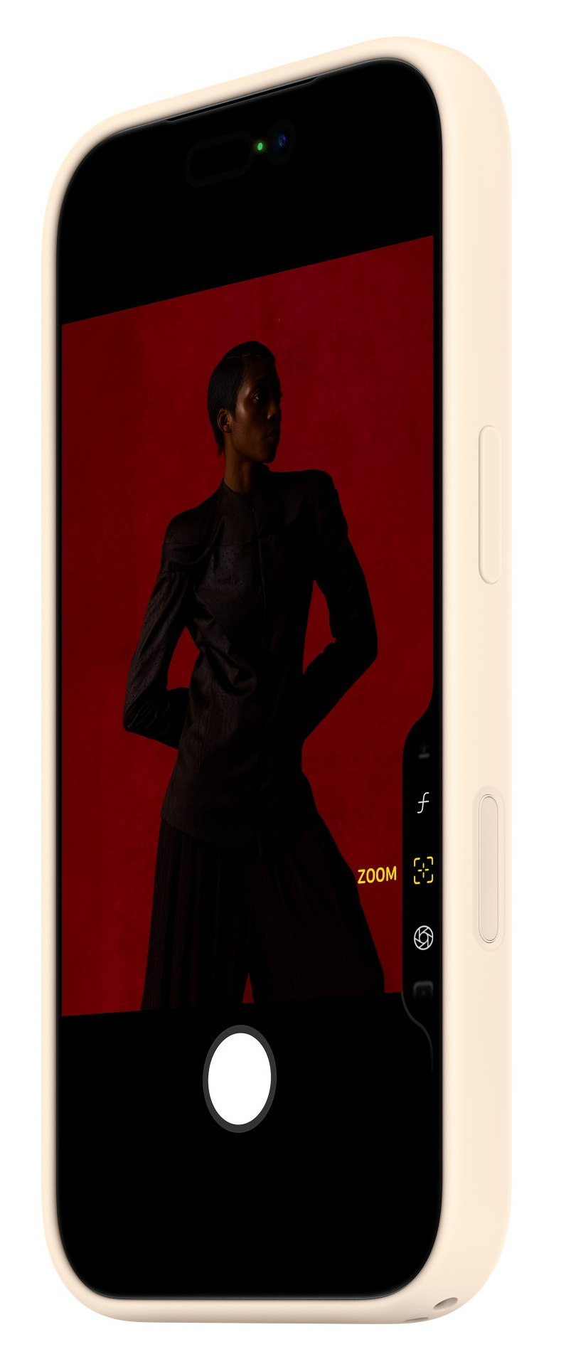 Osoba w ciemnym stroju pozuje na czerwonym tle na ekranie telefonu.