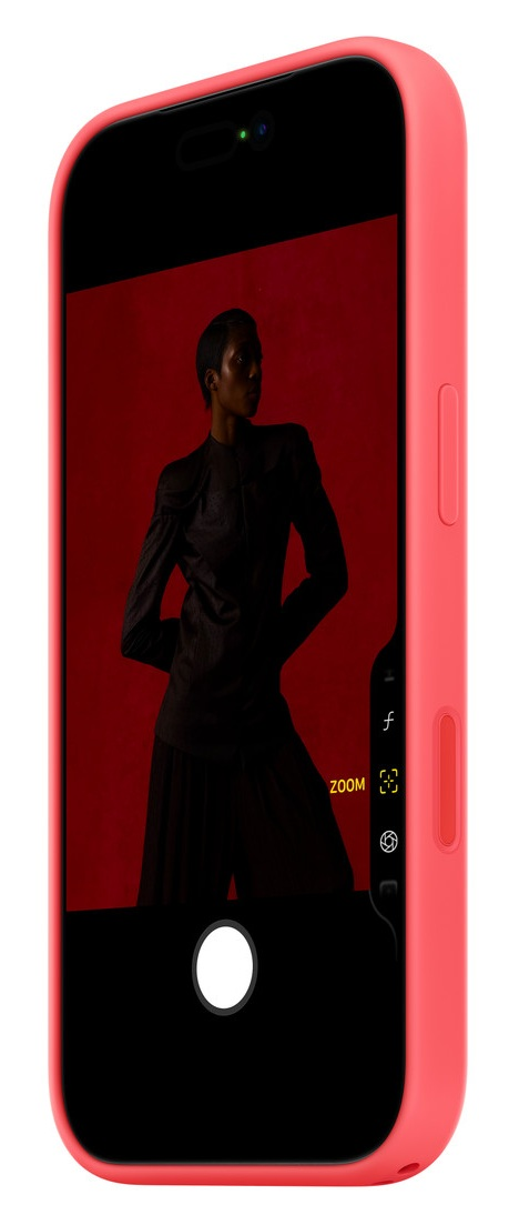 Smartfon w koralowym etui pokazuje modelkę na czerwonym tle.