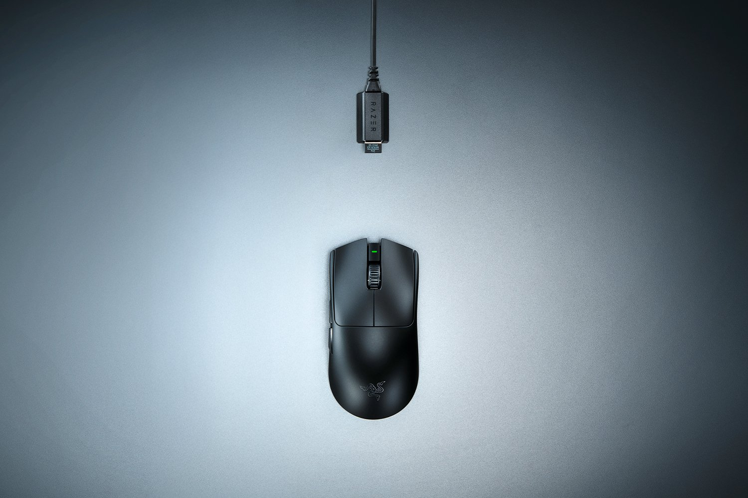 Ratón Razer negro y dongle USB sobre superficie gris.